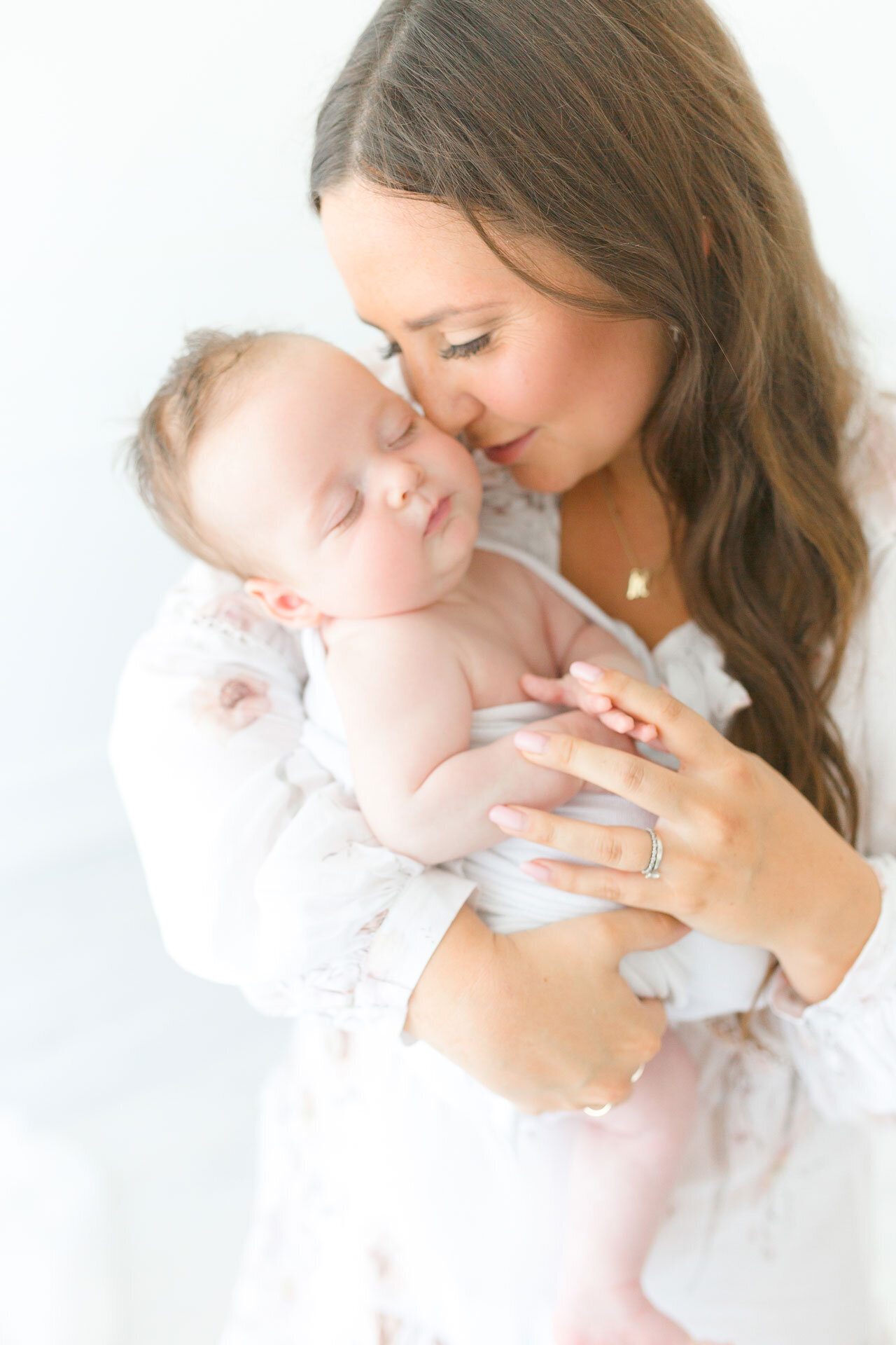 Edle Babyfotografie im Fotostudio Gütersloh nahe Bielefeld, Verl, Paderborn. Mama hält ihr Baby auf dem Arm und blickt es liebevoll an.