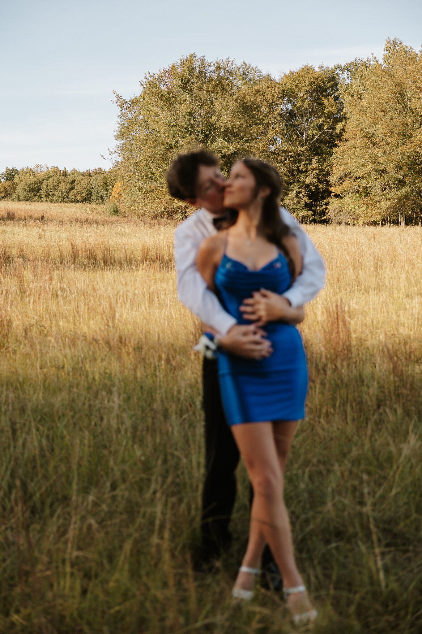 Outdoor homecoming photoshoot in Aiken SC - teen couple embracing in a golden field, with the girl wearing a blue HOCO dress.