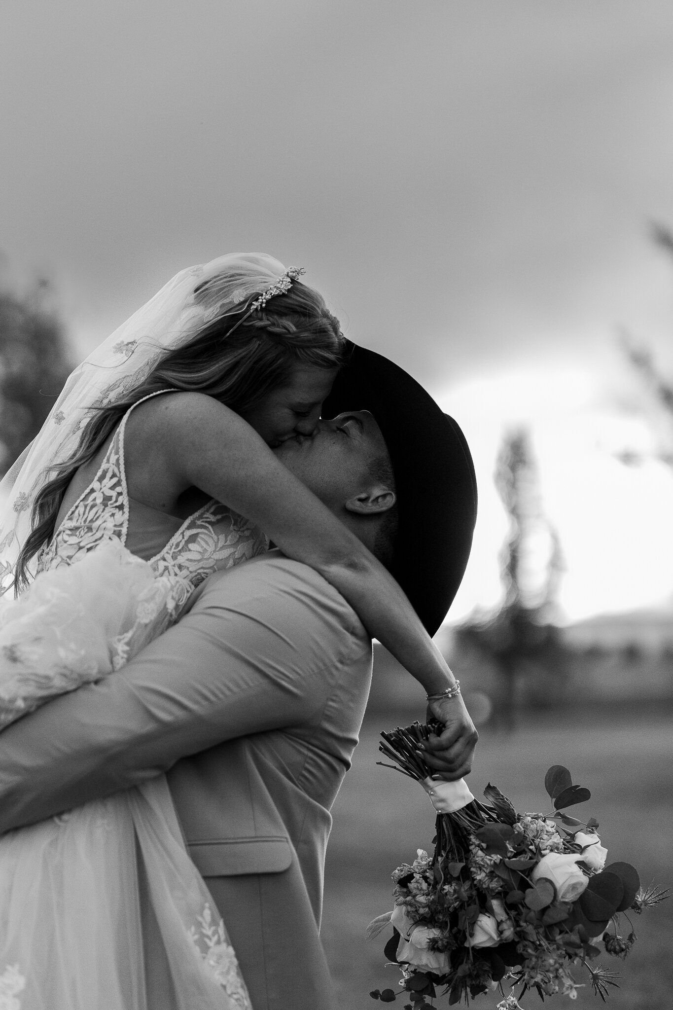 Romantic black and white candid of the bride and groom sharing a quiet kiss during their wedding at Absolute Prestige in Loma, Colorado