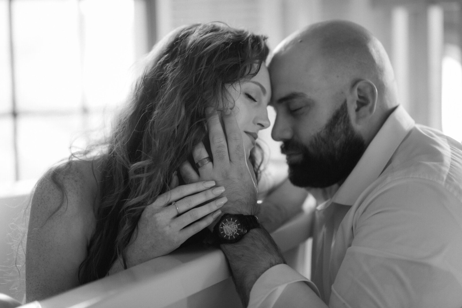 groom embracing the bride and touching her face black and white image. Prepping for their elopement