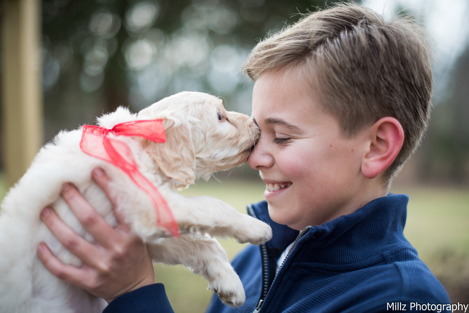 young boy being licked on the nose by his new puppy photographed by Millz Photography in Greenville, SC