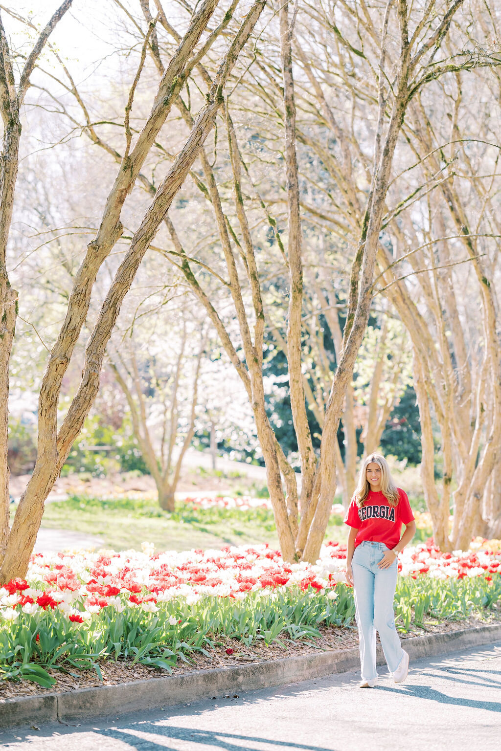 Girl in jeans and UGA shirt stands in botanical gardens in Athens