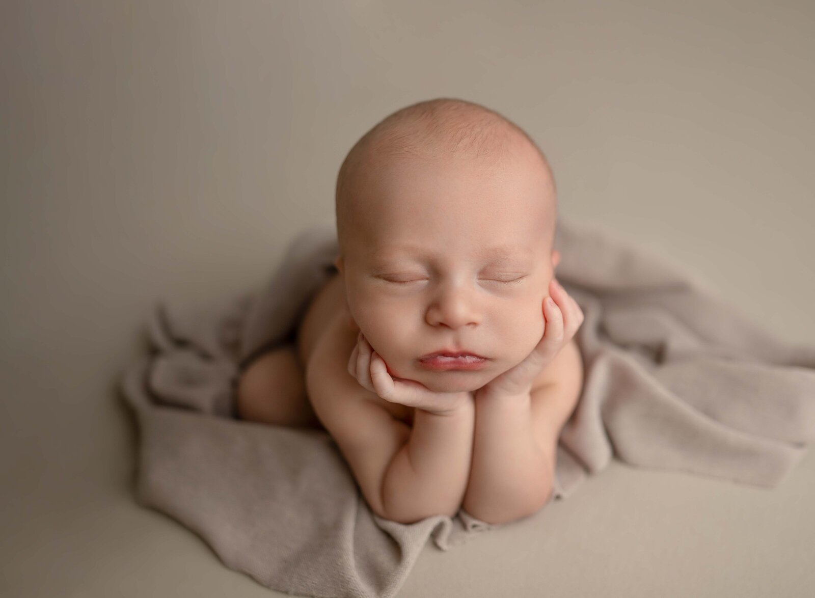 Newborn baby boy sleeping in froggy pose. Photo taken by Jenni Nikki Photography at Marietta Newborn photo studio.