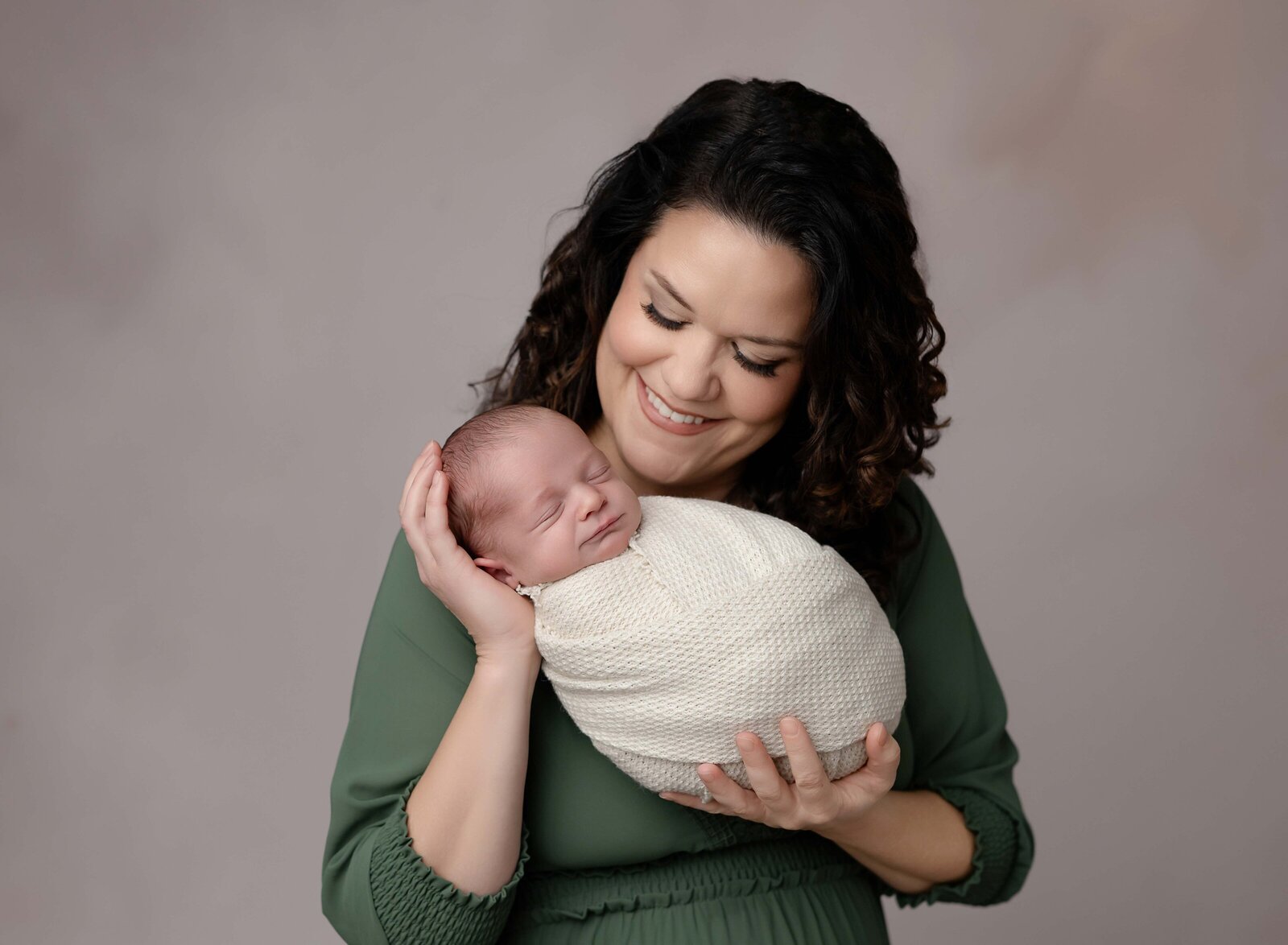 Newborn photo of Mom holding baby and smiling at them lovingly. Photo by Jenni Nikki Photography, Marietta Newborn photographer.