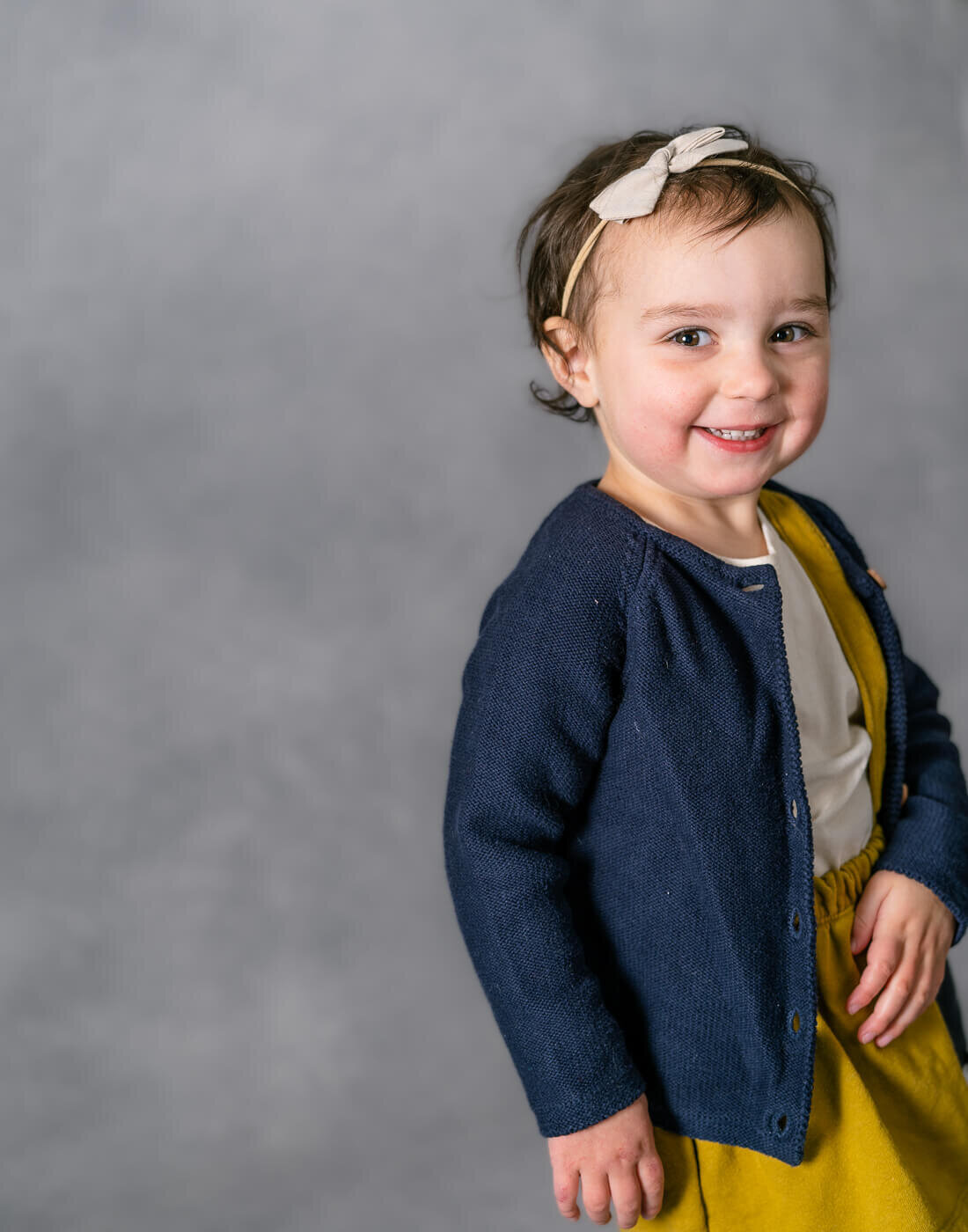 A child smiles while walking out of the frame.