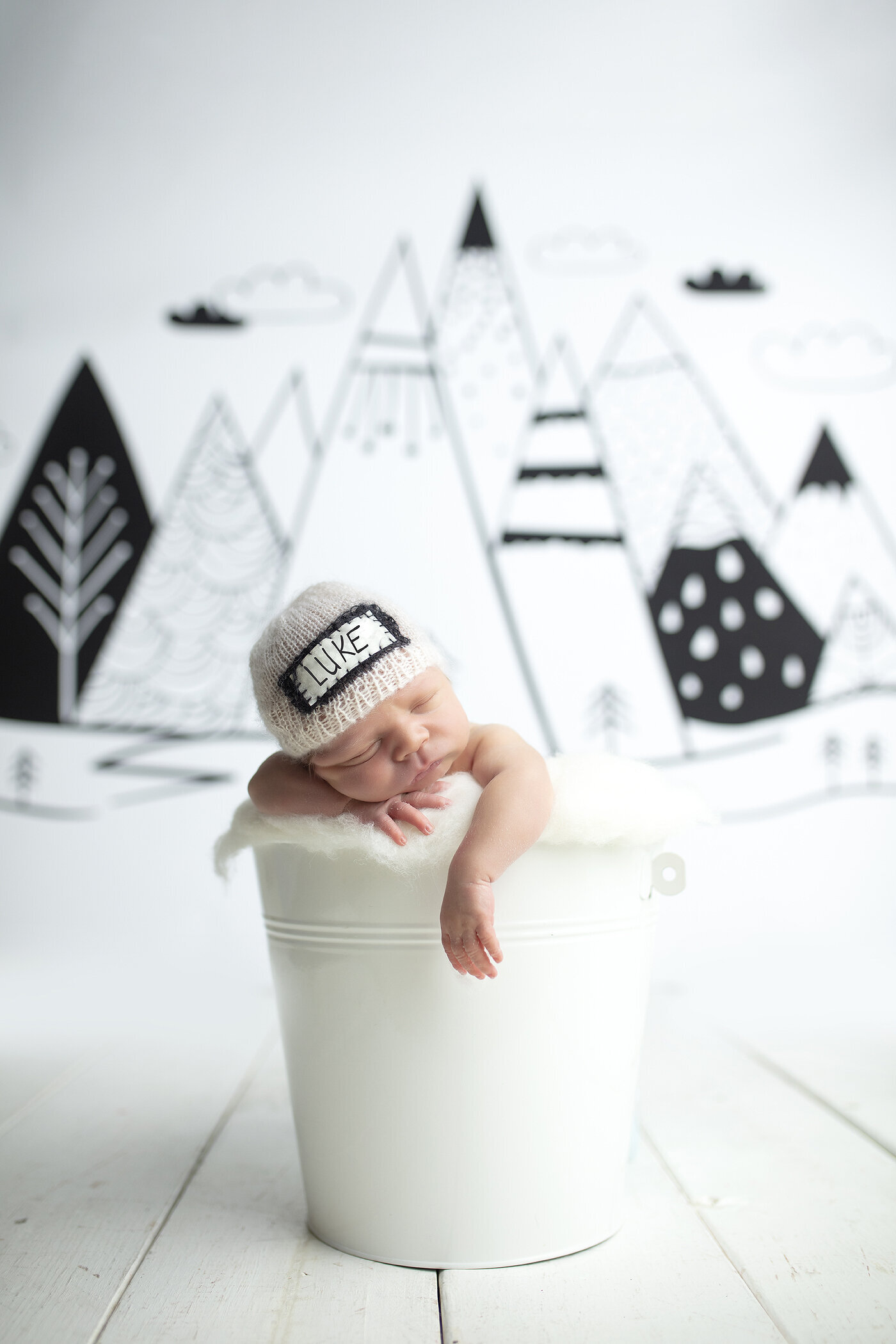 Newborn boy in white bucket, a dallas newborn photographer.