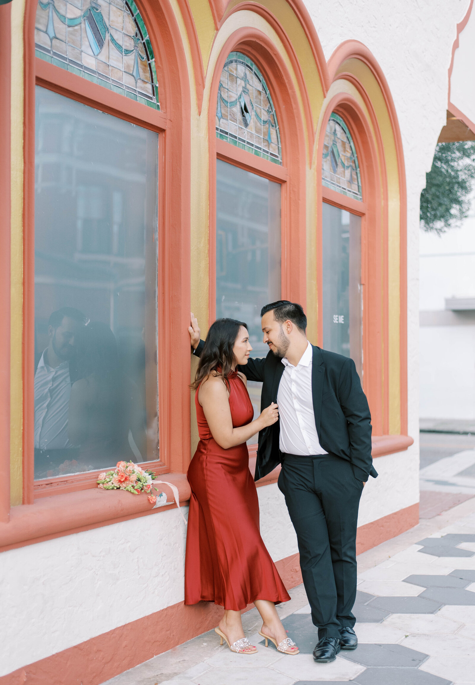 couple leaning against window during engagement session