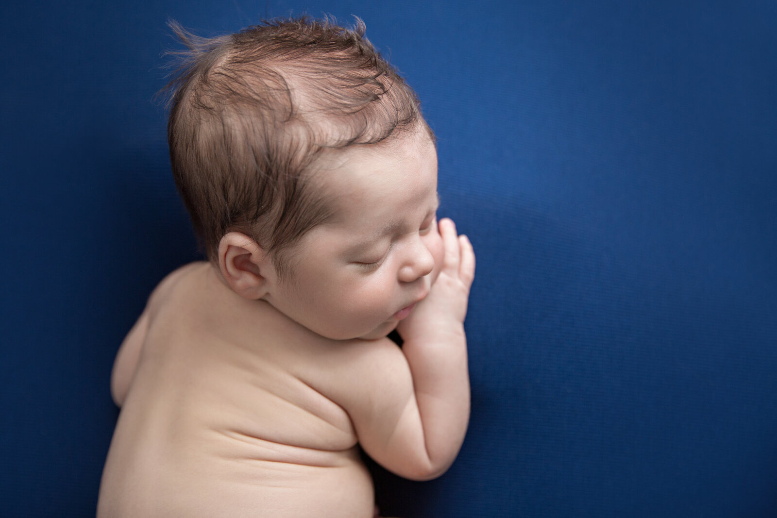 sleeping newborn baby posed on navy fabric with back wrinkles