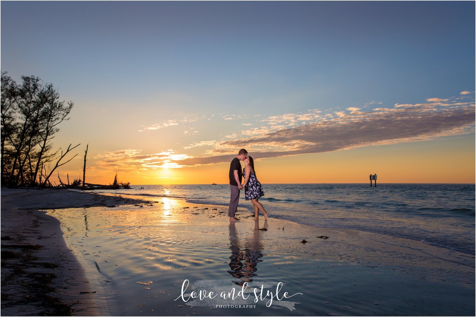 Beer Can Island Engagement Photo of couple kissing by the water at sunset