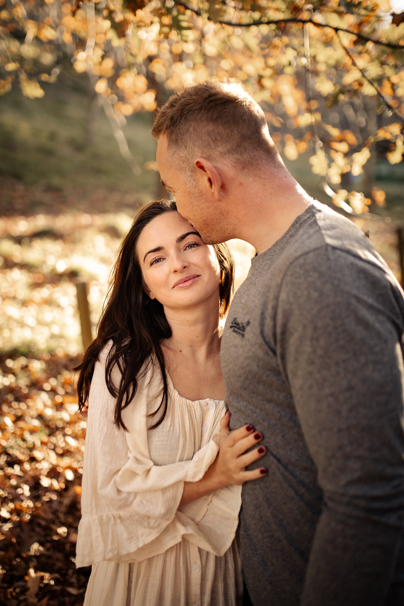 Couple embracing amidst a blanket of vibrant autumn leaves at Dolbel Reserve, Taradale, Hawke’s Bay – romantic outdoor photography capturing the rich colours of native bush and panoramic views of Napier and Hastings, ideal for couples and family sessions by a local Hawke’s Bay photographe