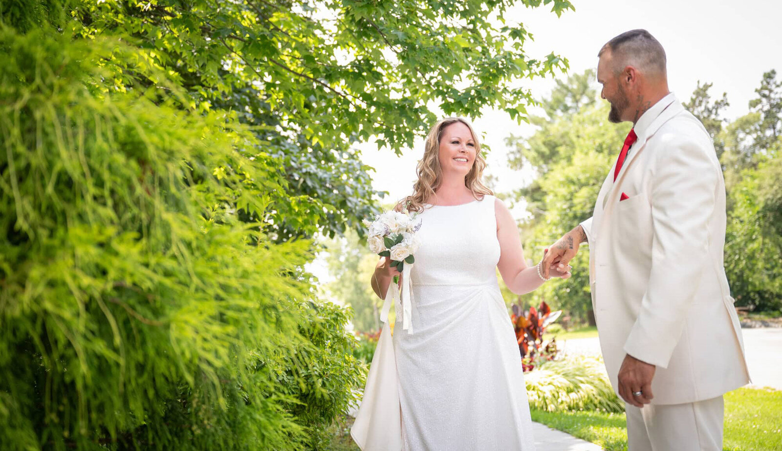 groom leads bride by the hand near plants
