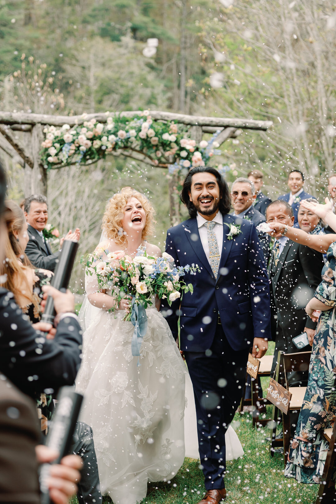 bride and groom exiting ceremony laughing walking through confetti