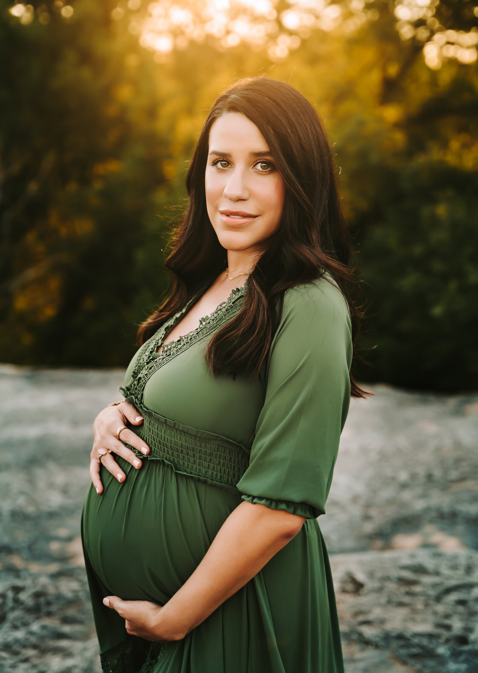 Maternity Photographer, a pregnant woman holds her belly near the river