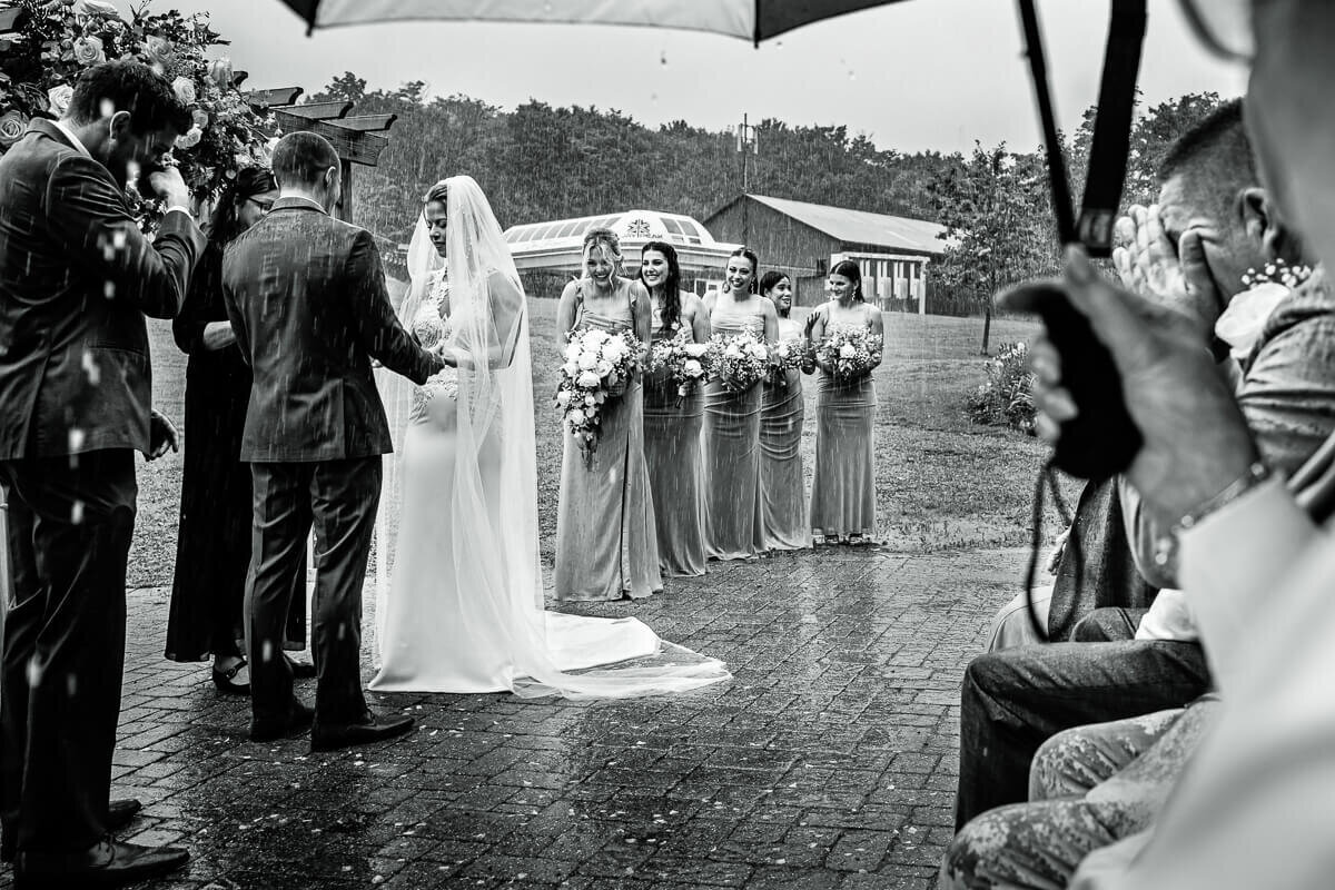 A wedding ceremony takes place during pouring rain at Jay Peak Resort in Vermont, captured by Eaton Photo