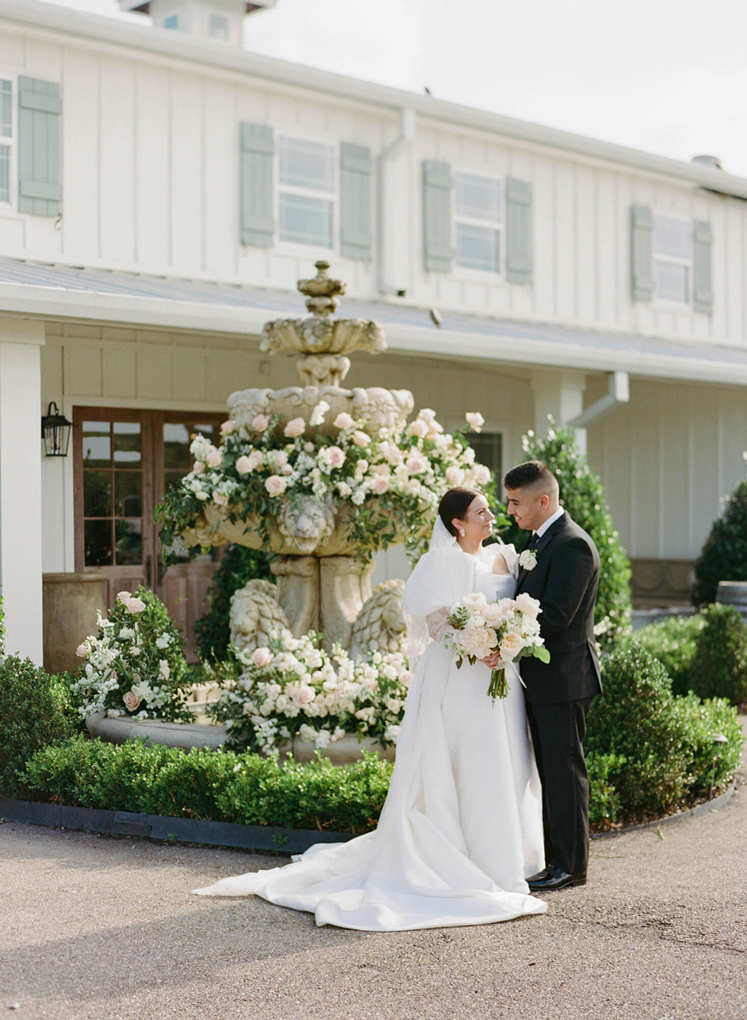 bride and groom standing in front of fountain