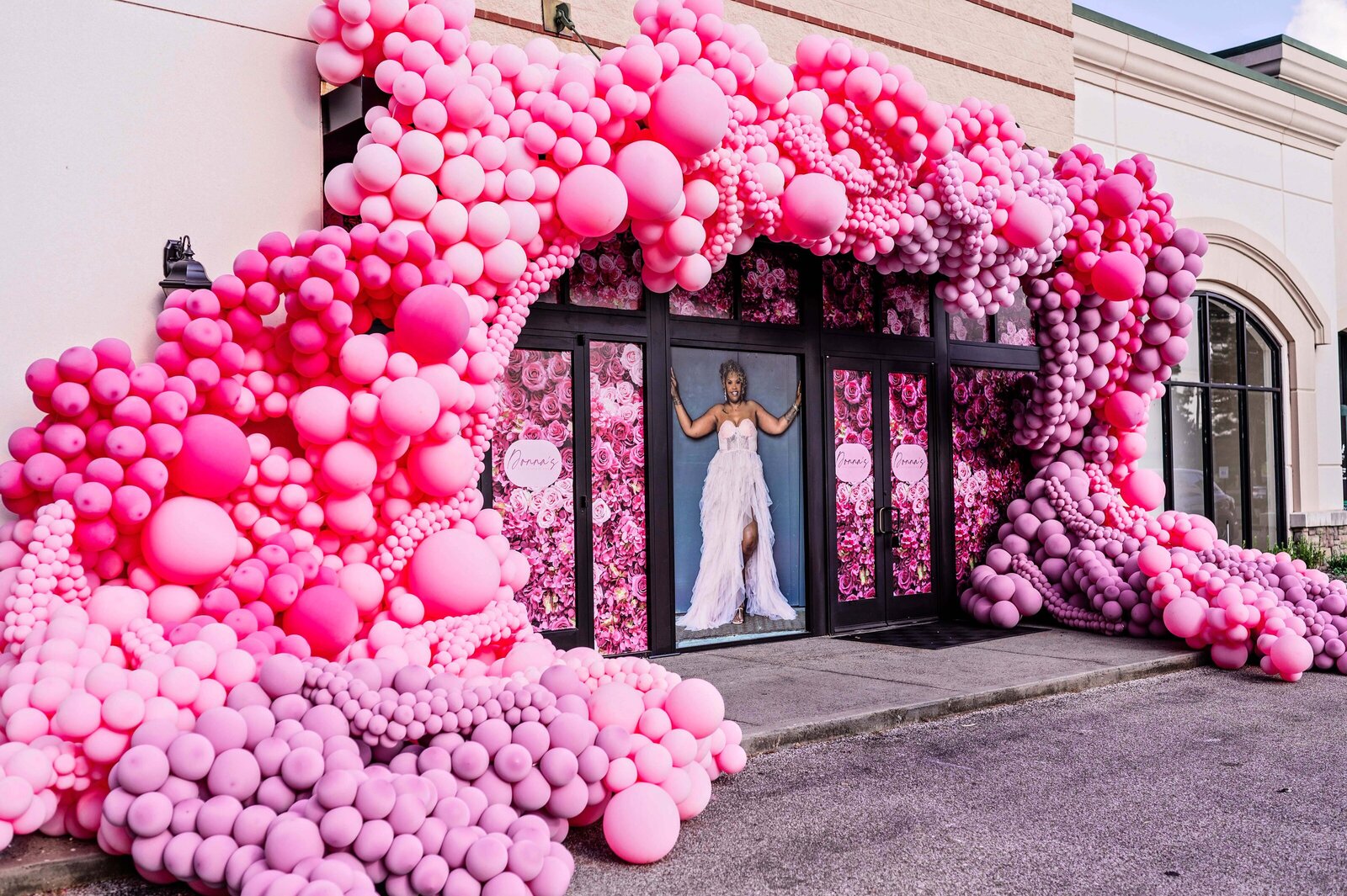 Vibrant pink balloon installation at Palace at Cordova in Memphis featuring cascading balloon garlands and floral window wraps for a luxury grand opening event, styled by Wells Design Co.