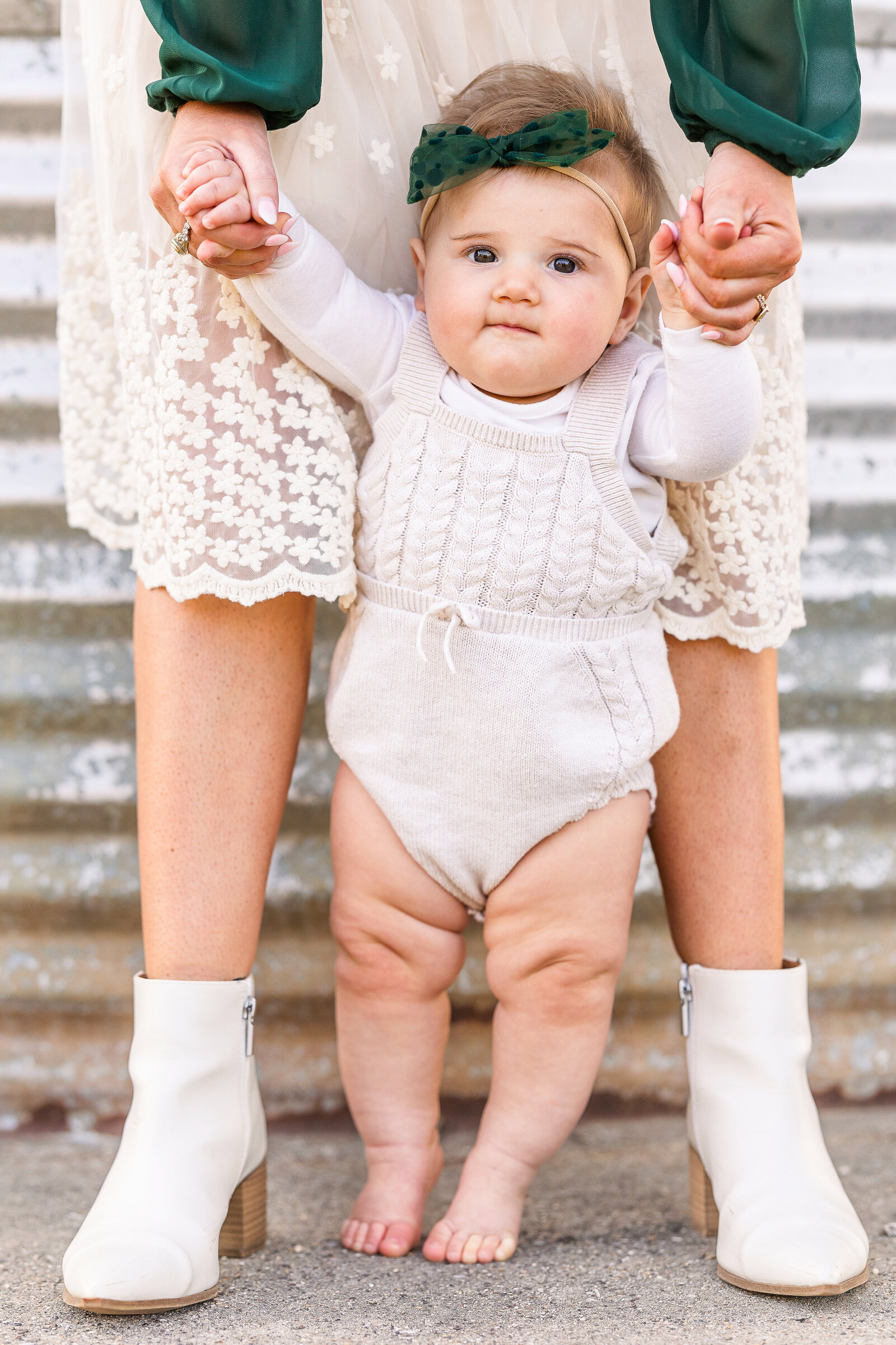 baby-standing-between-her-mothers-legs-holding-hands