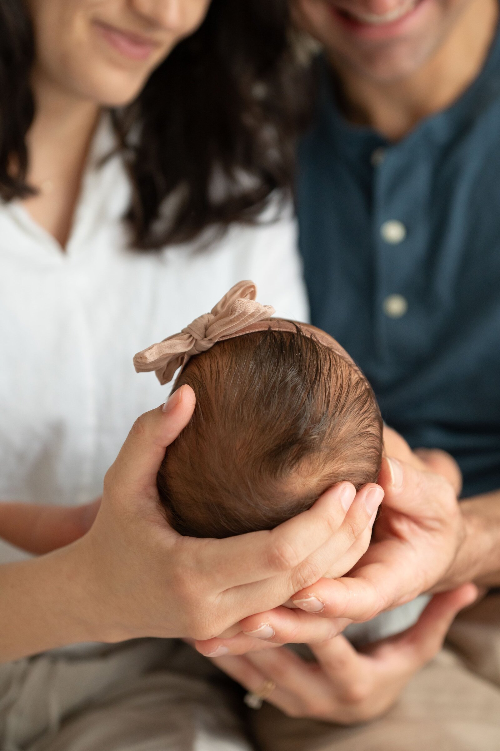 new parents holding babies head in their hands in a Cockeysville, Maryland photography studio