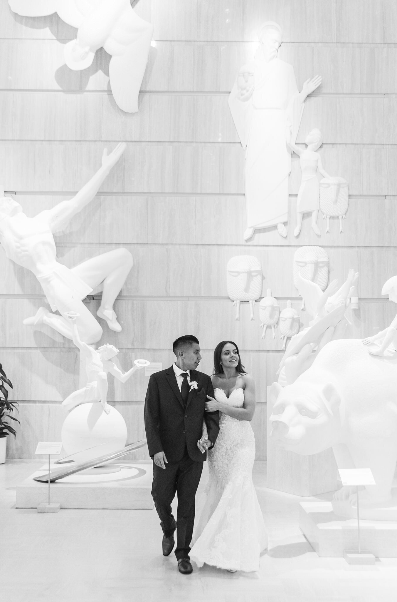 bride and groom walking through an art museum