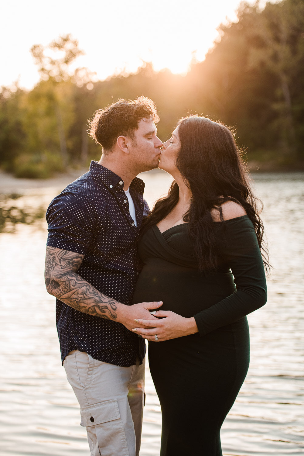 maternity couple at sunset kissing