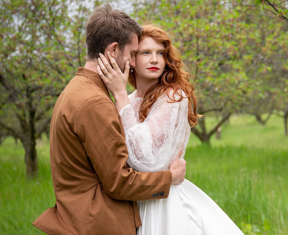 bride and groom in a grove of trees while bride with bright lipstick looks away