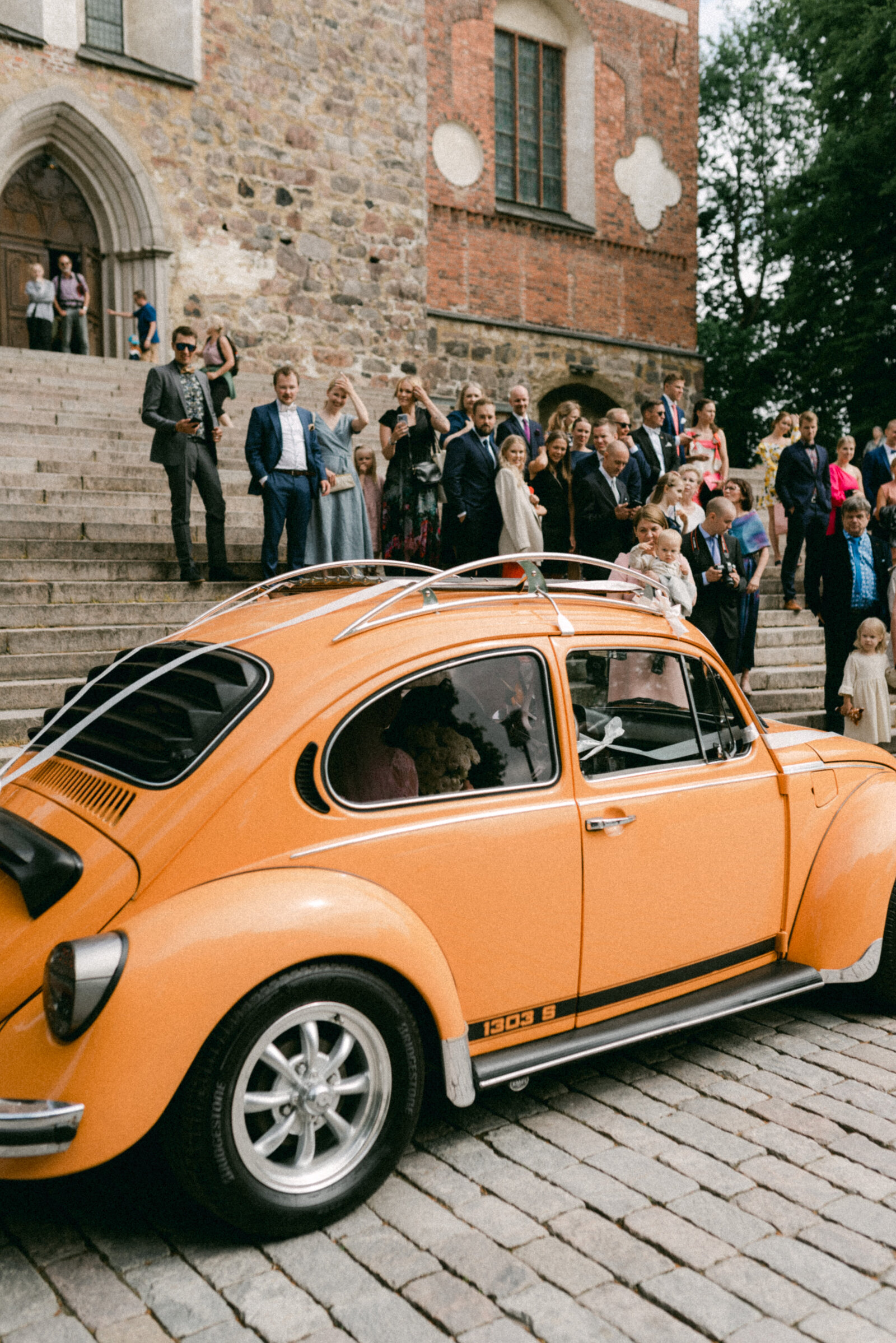 Wedding car, orange volkswagen beetle in front of Turku cathedral after wedding ceremony. Documentary image captured by wedding photographer Hannika Gabrielsson