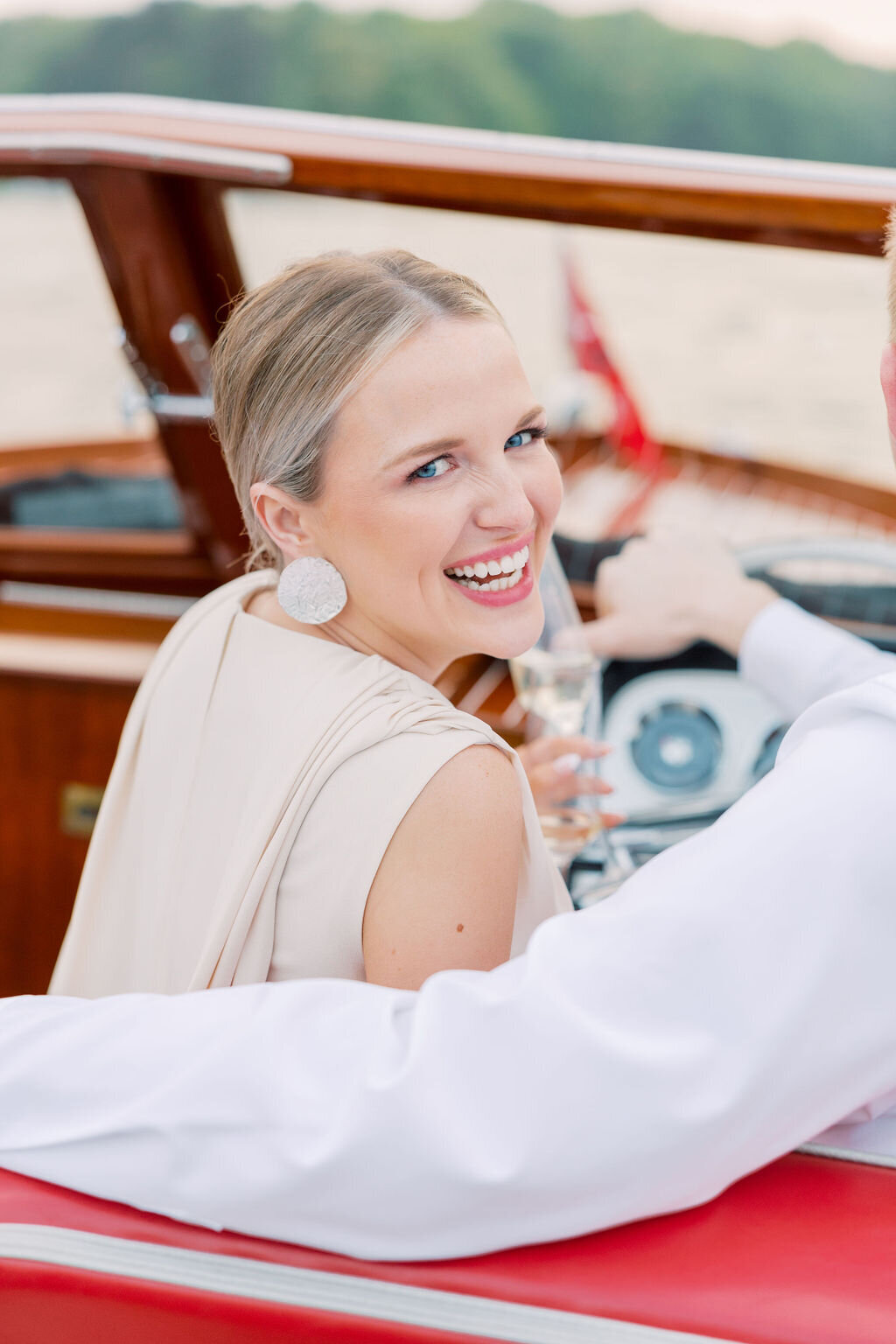 Woman in white dress smiles with champagne on boat engagement in Georgia