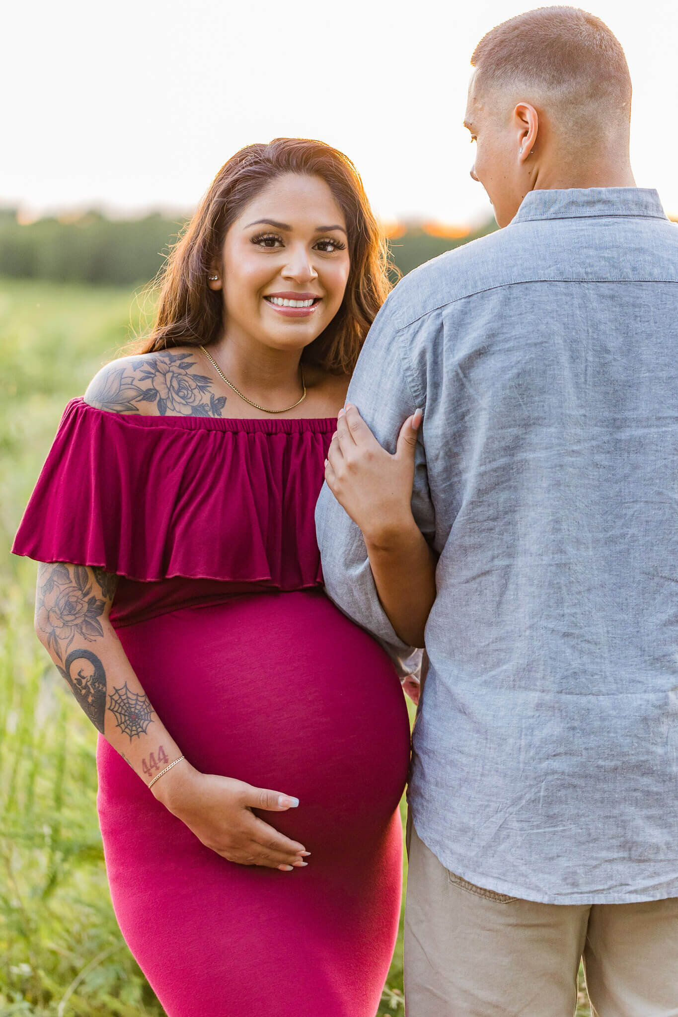 A pregnant couple posing for their Northern Virginia maternity photography session at a park at sunset.