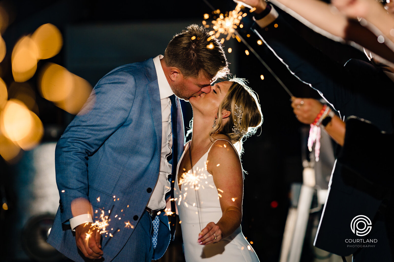 couple kissing with wedding sparklers in hands