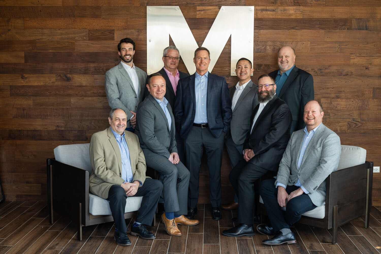 Team of professionals posing in front of an M backdrop
