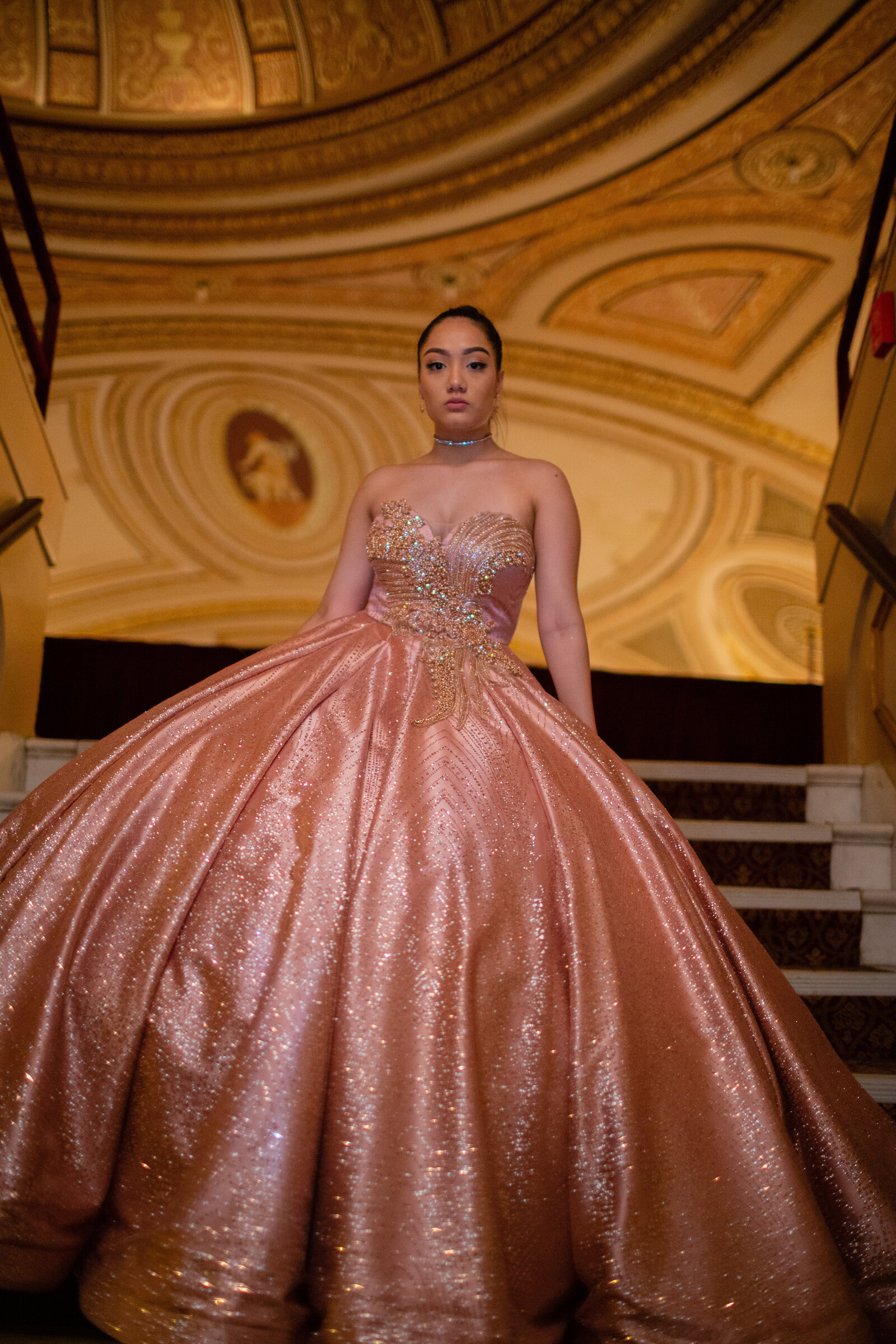 A captivating portrait of a quinceañera in her sparkling gown, standing gracefully on the grand staircase of the Ohio Theater at Playhouse Square in Cleveland, Ohio. Showcasing timeless elegance and the historic venue's opulence.
