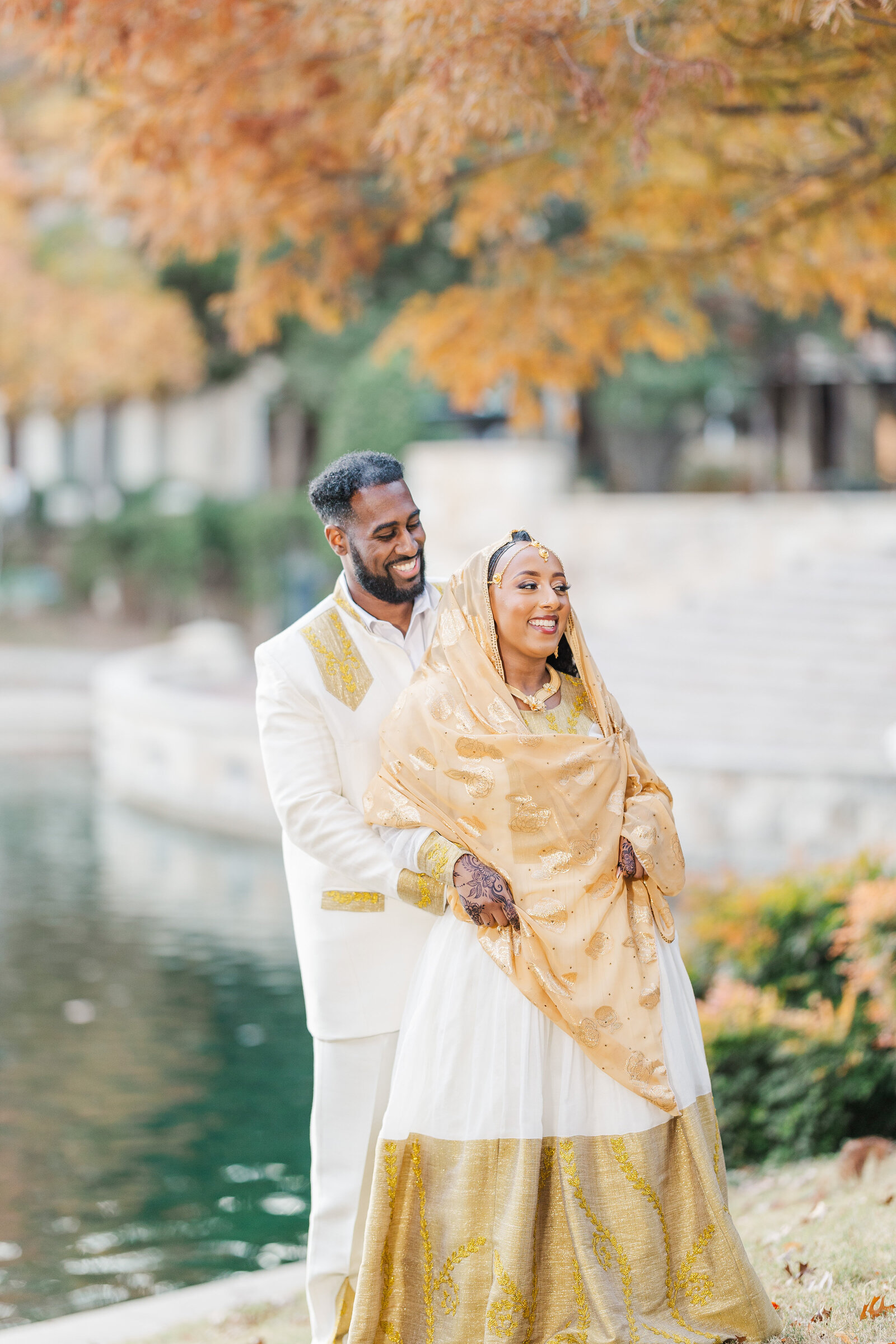 Groom-holding-bride-from-behind-infront-of-lake