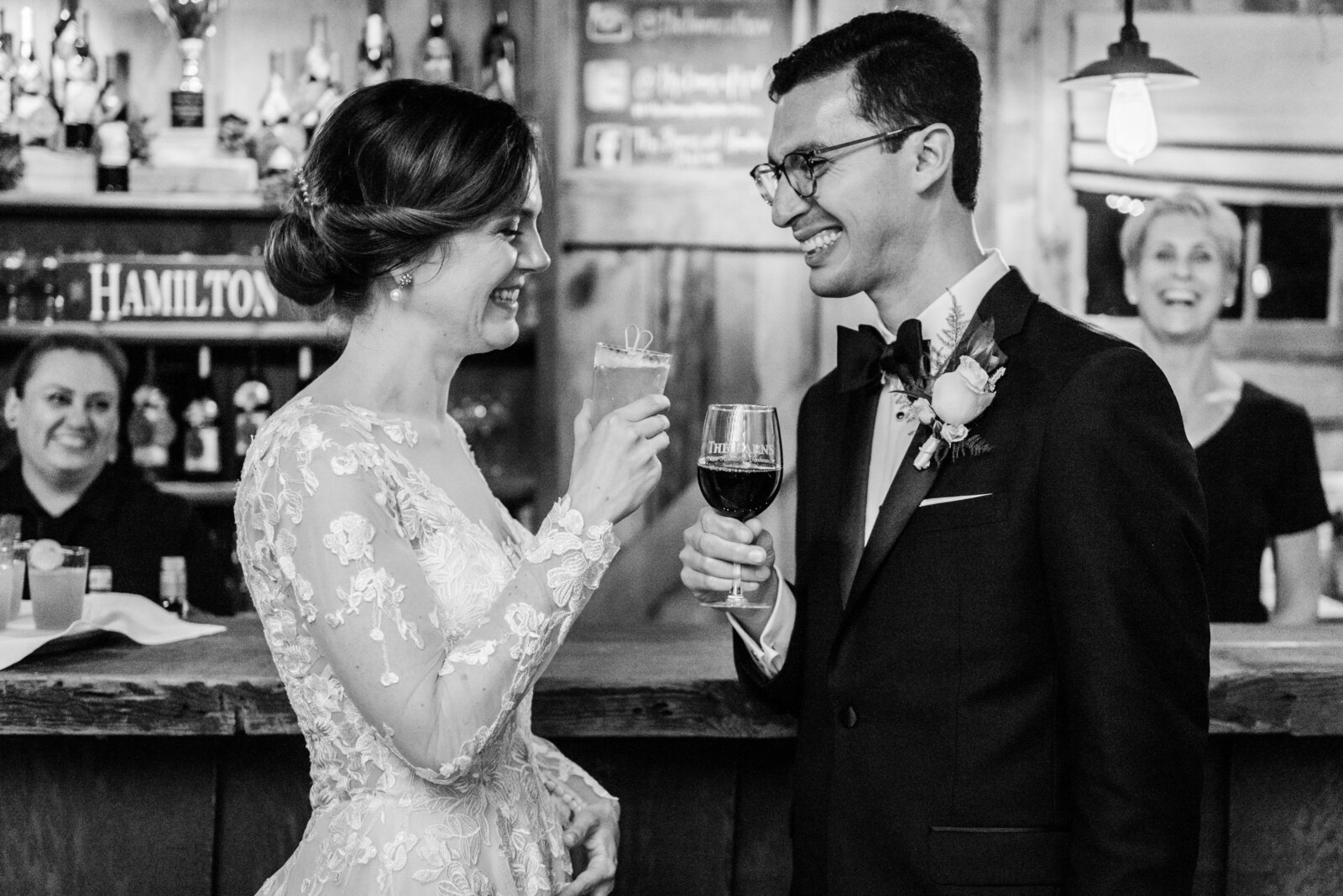 A bride and groom toast their drinks at the bar during their wedding at The Barns at Hamilton Station Vineyard in Loudoun County