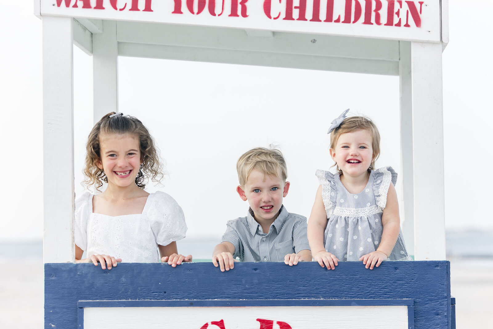 three siblings posing inside lifeguard stand photographed by new jersey photographer ally kimpton