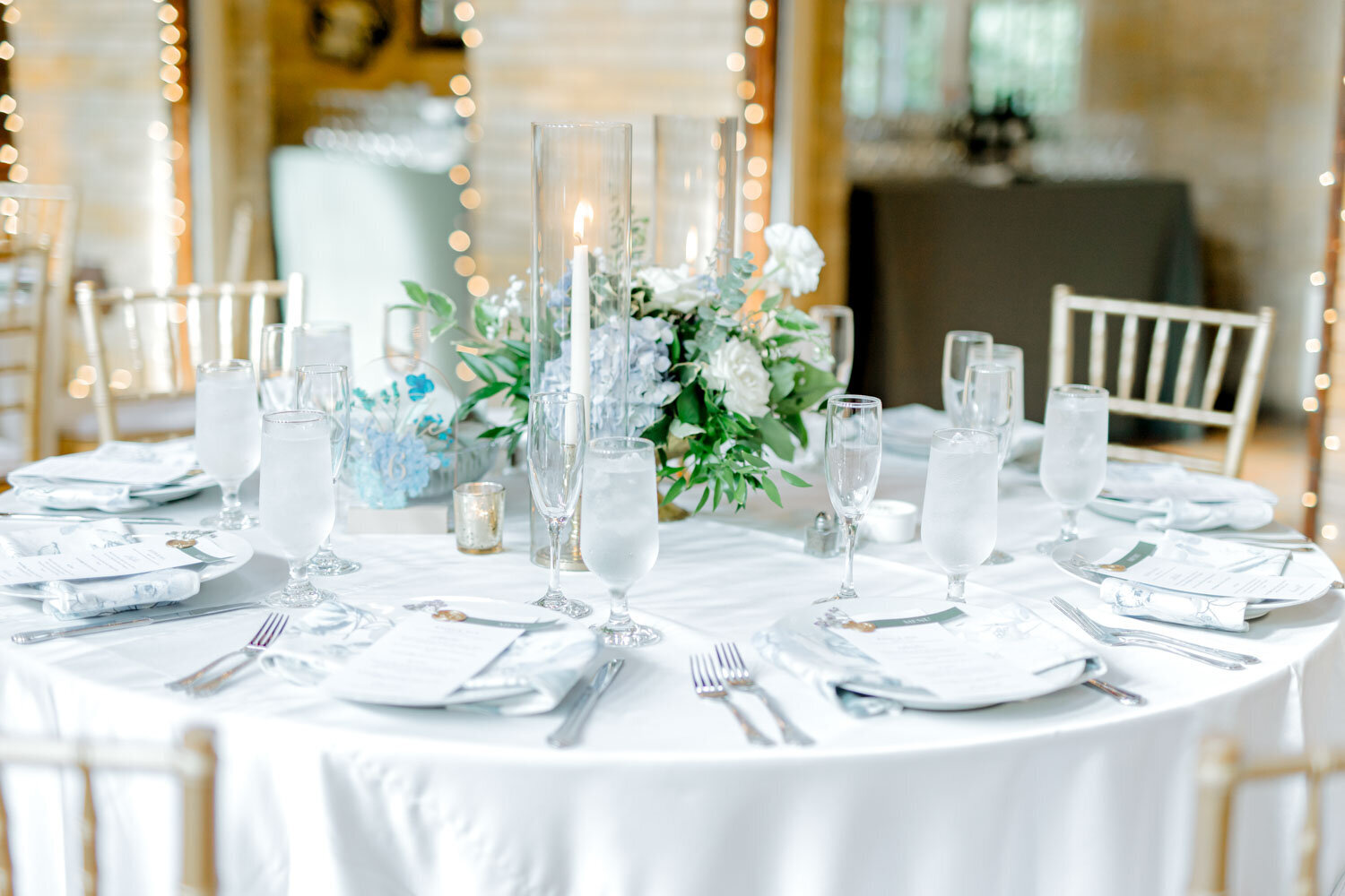 Wedding reception table with white linens, candles, and floral centerpiece