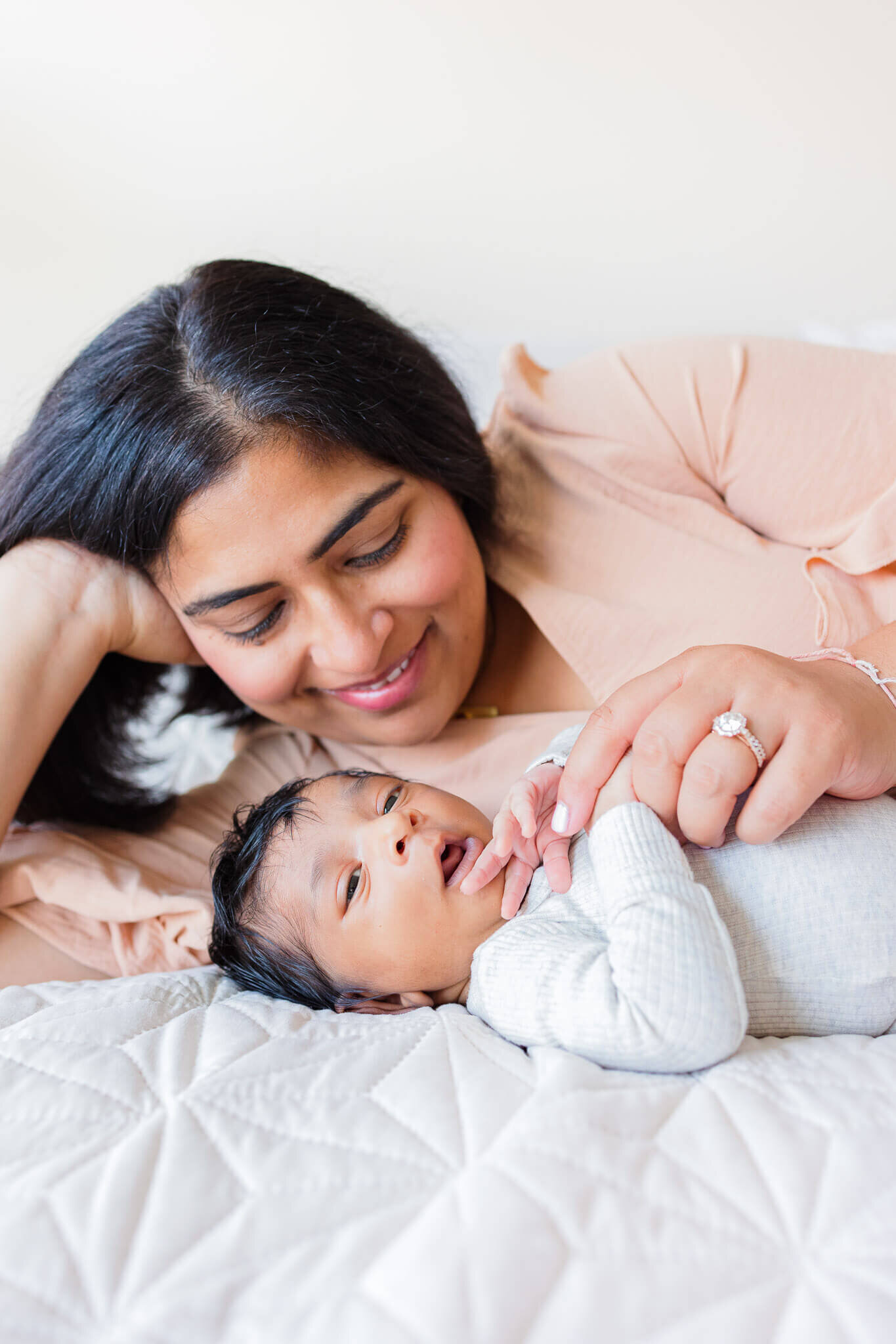 A close-up of a mom and her newborn son snuggling in bed.