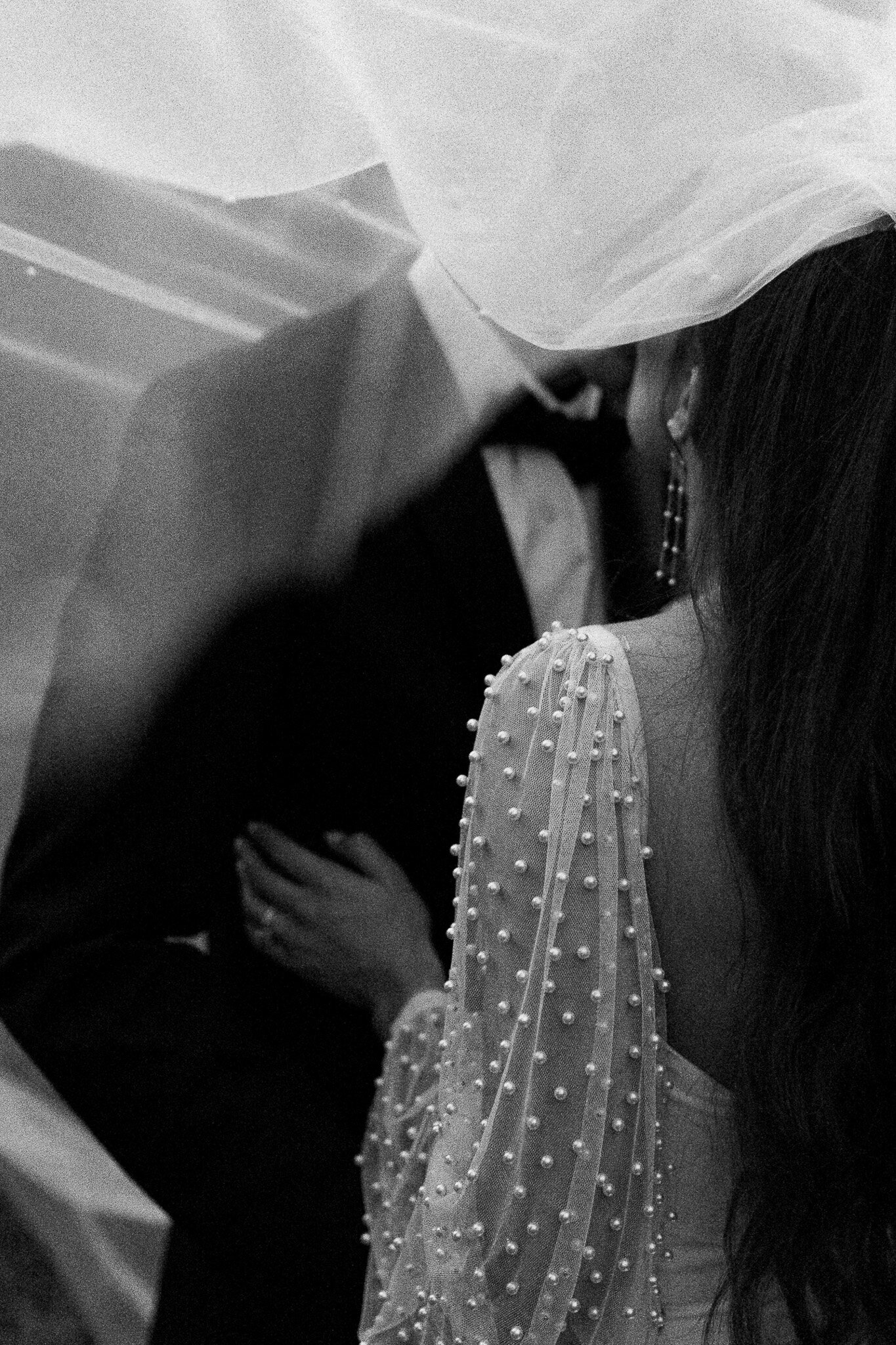 Bride in a long sleeve pearly bridal gown kissing the groom