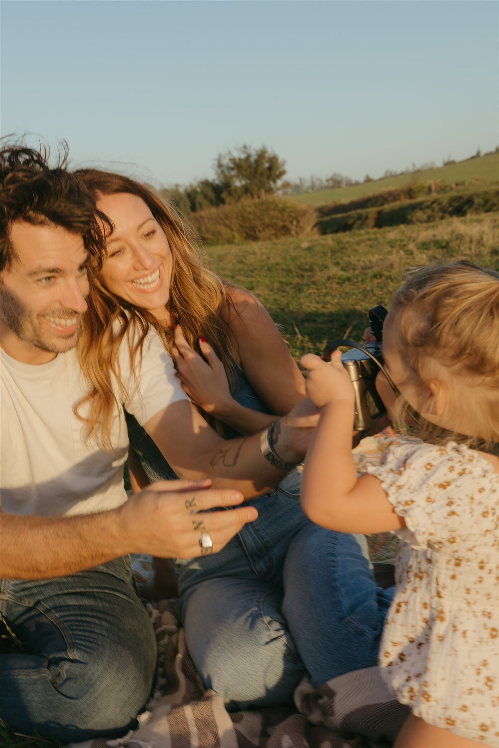 Family embracing during a Maui cliffside family photo shoot, natural light highlighting denim and soft neutrals.