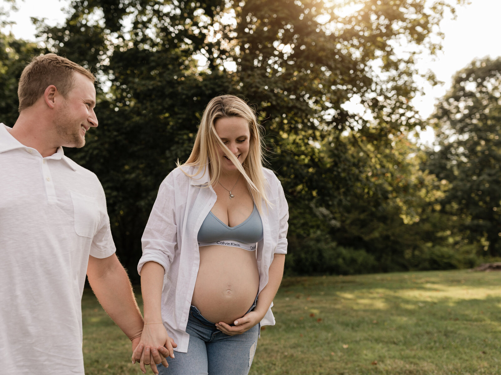 mother and father walking and holding hands and  belly for maternity photoshoot