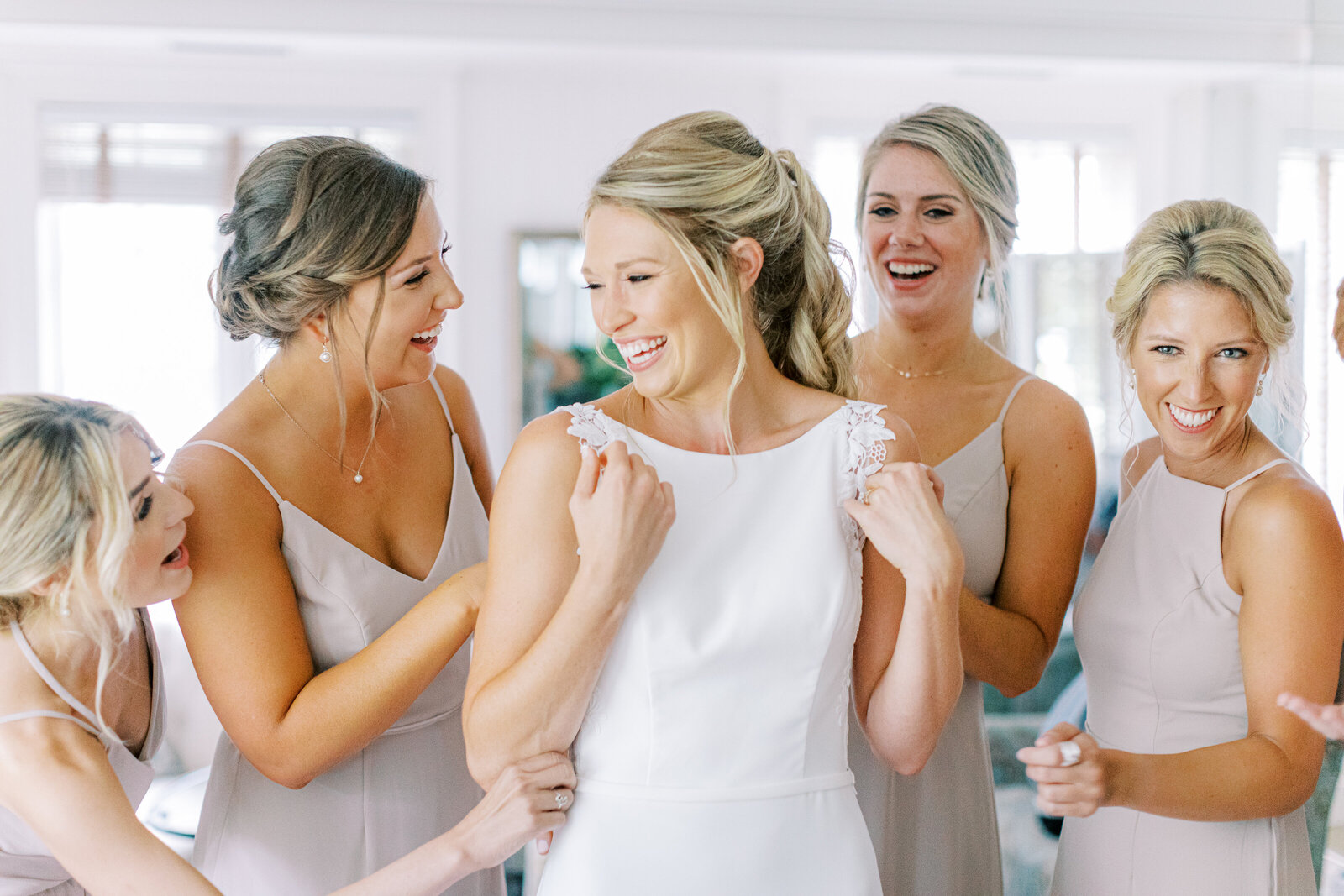 Bride laughing with bridesmaids before ceremony.