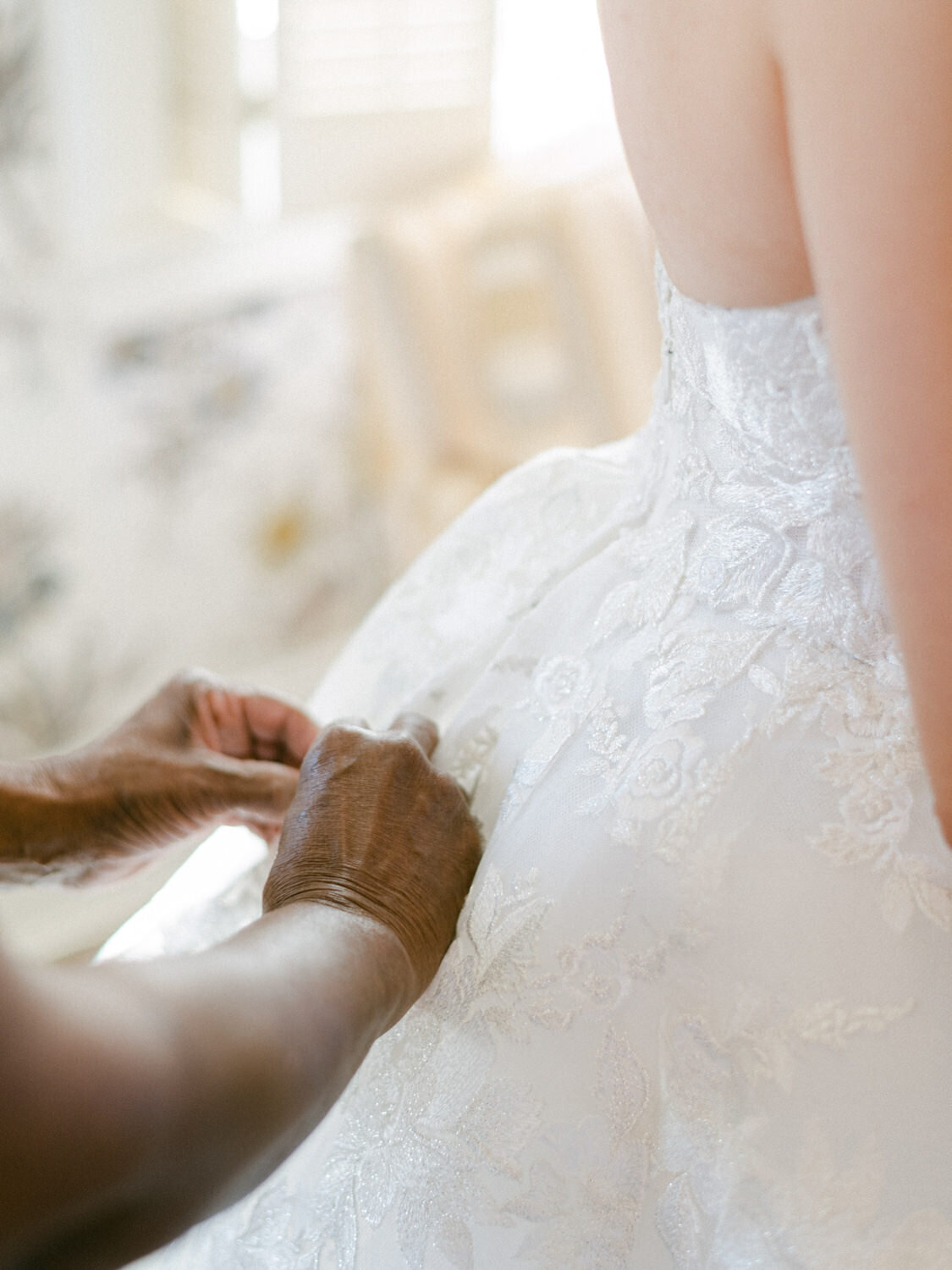 Bride buttons up daughter's wedding dress.
