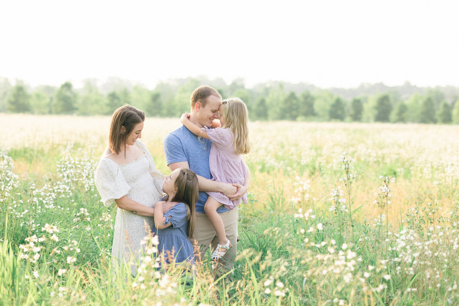 Portrait of a family of four playing in a field of white wildflowers during their family portraits with missy marshall photography