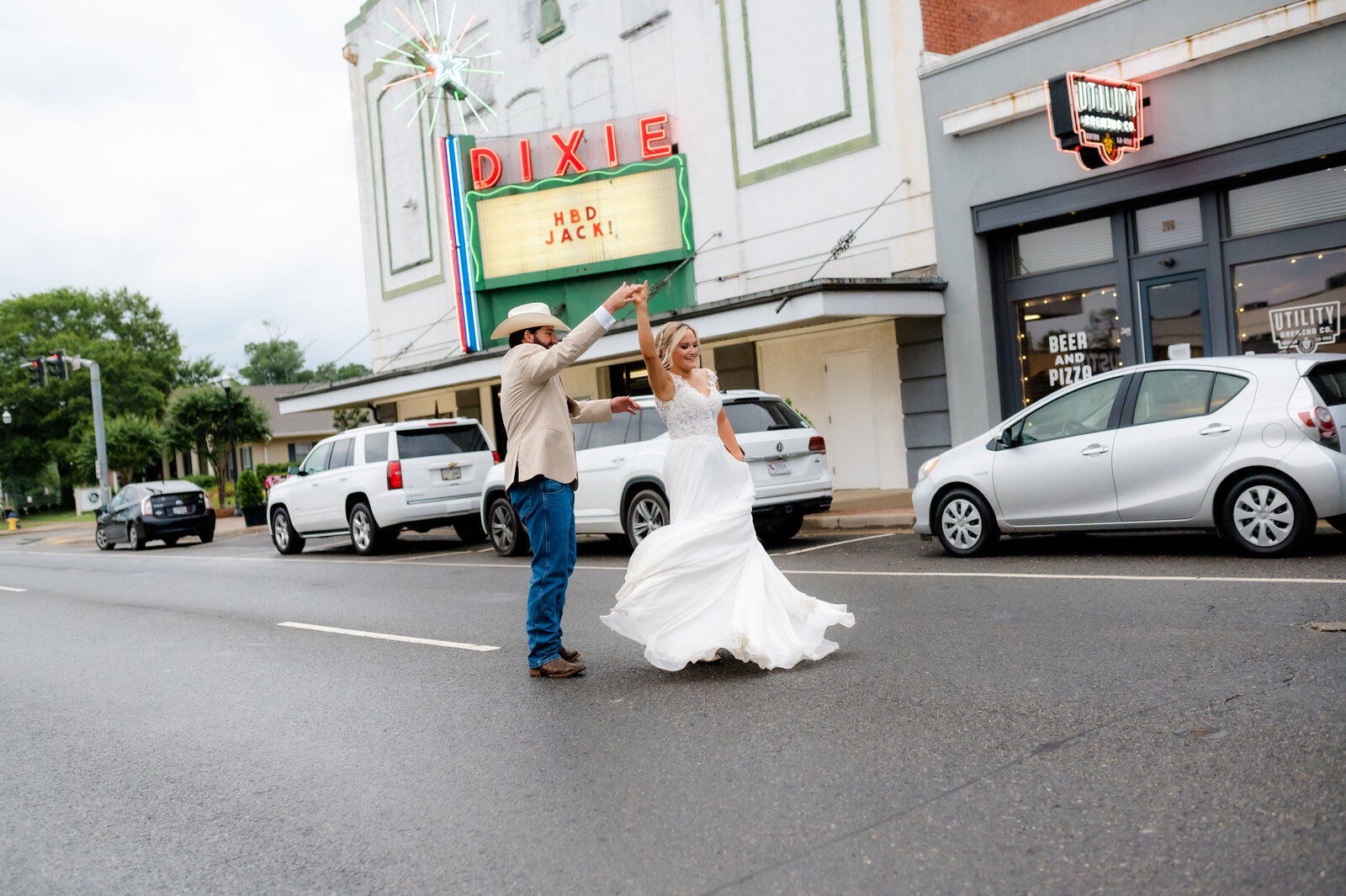 groom twirling his bride as they dance int he streets downtown together
