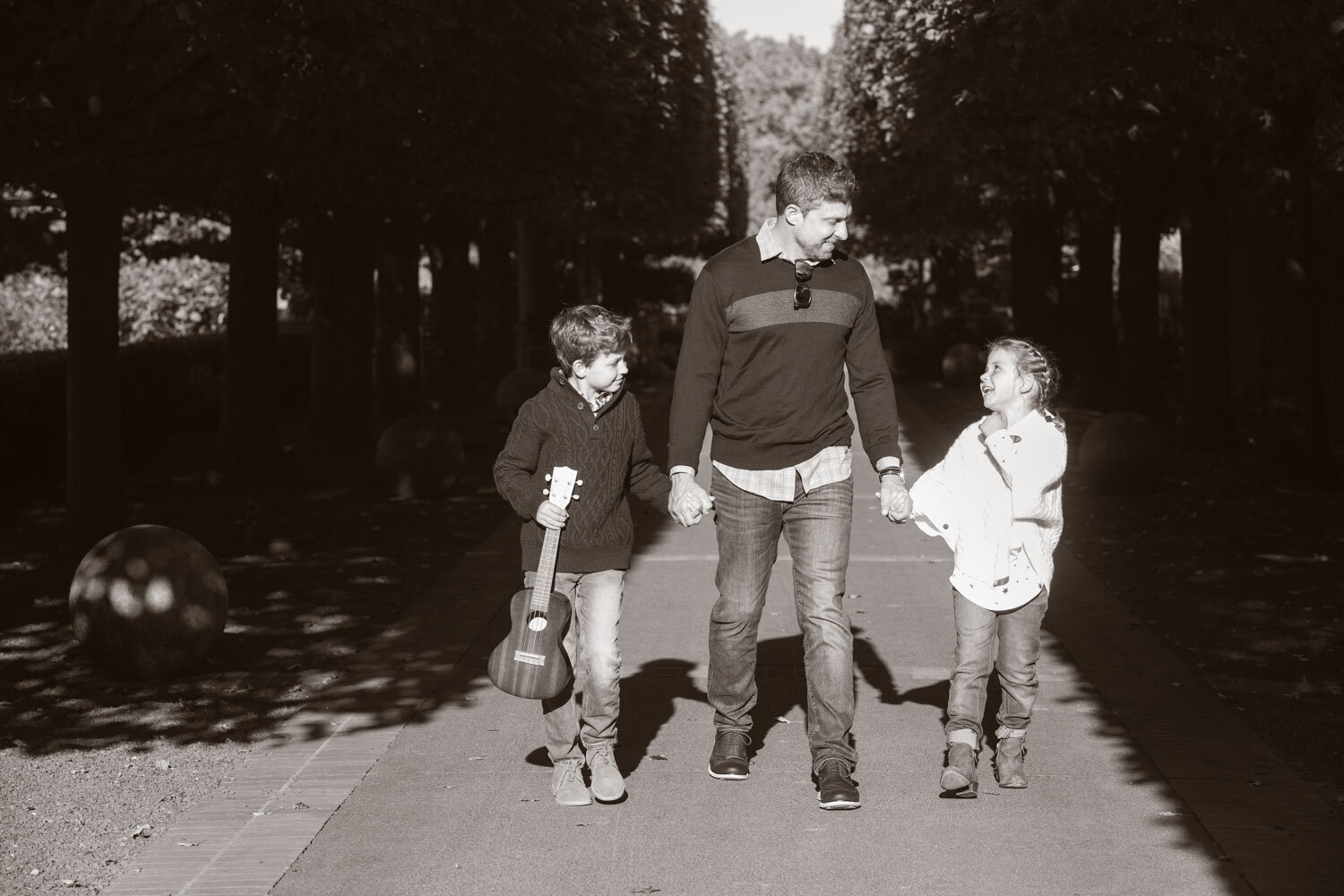 A man holding a guitar walking with two children