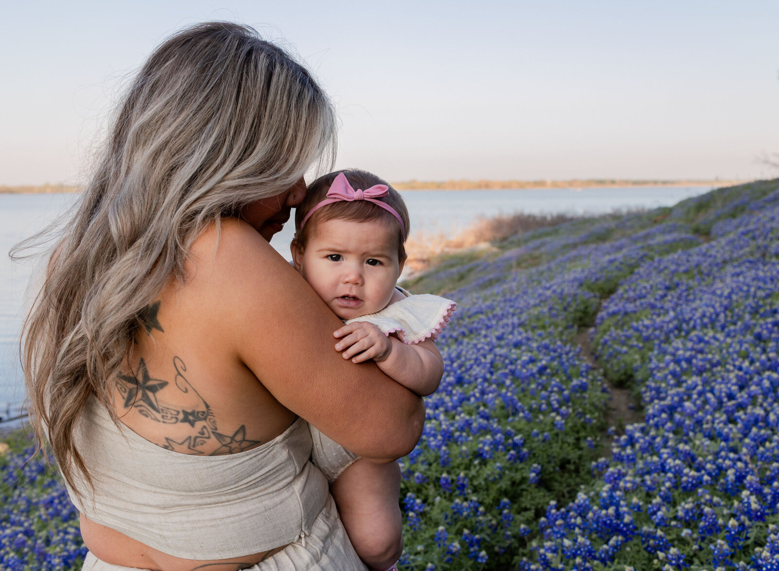 mother snuggling baby in bluebonnets