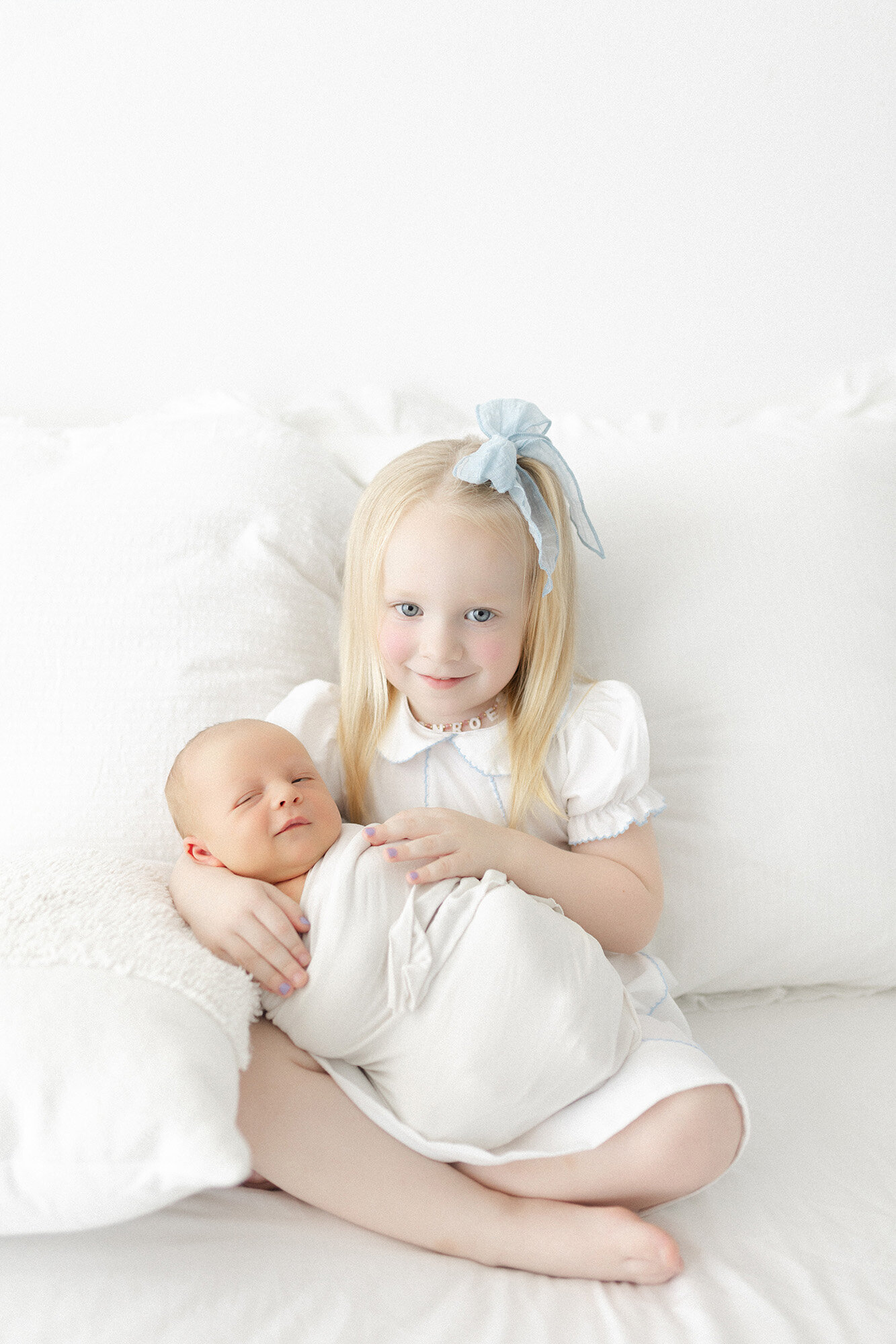 Big sister cuddling newborn baby brother during professional Grand Forks photo session