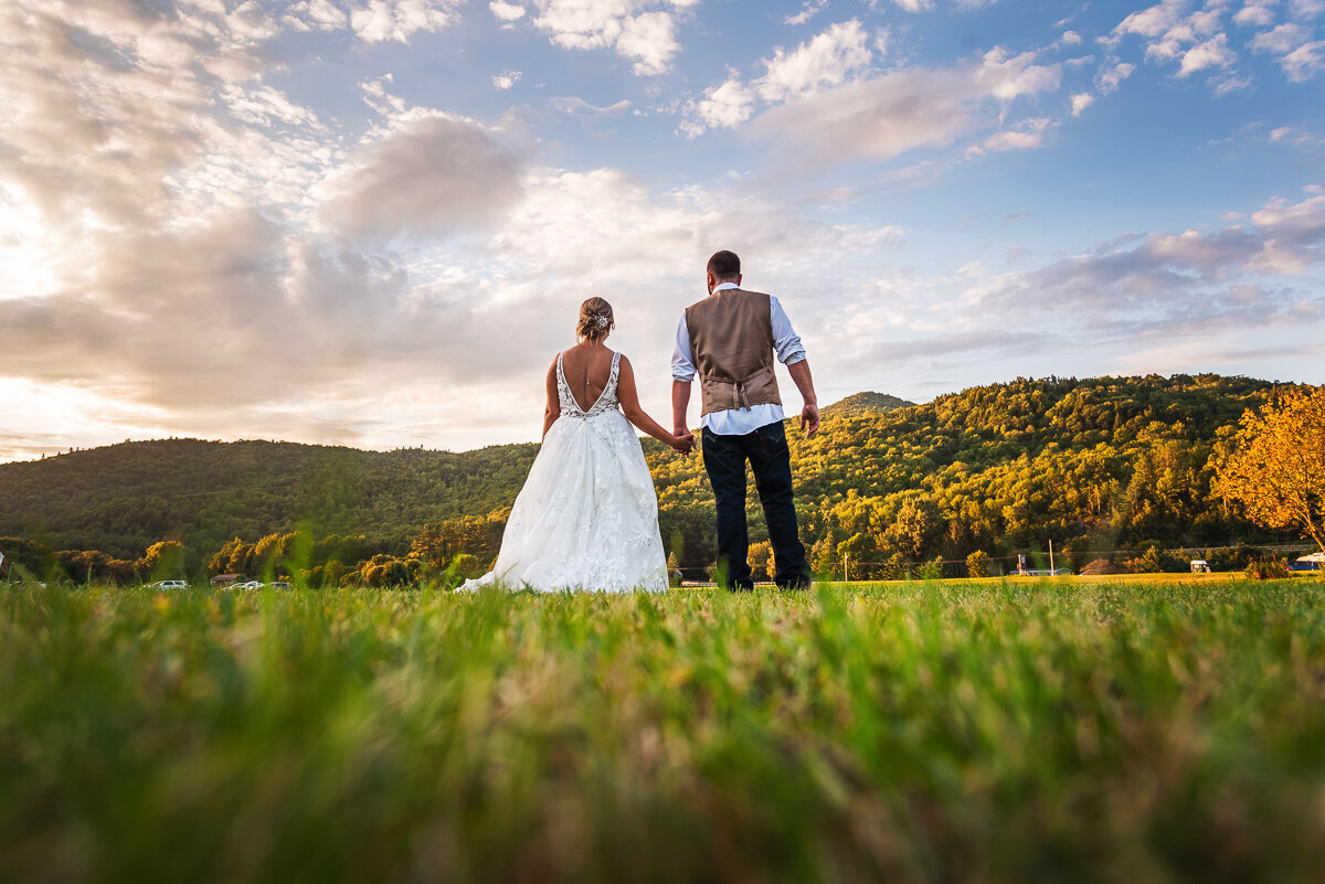 Wedding couple holding hands looking at mountains in Vermont