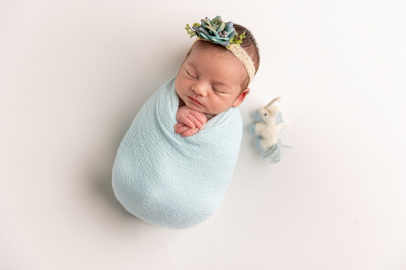 baby wrapped in blue swaddle with headband