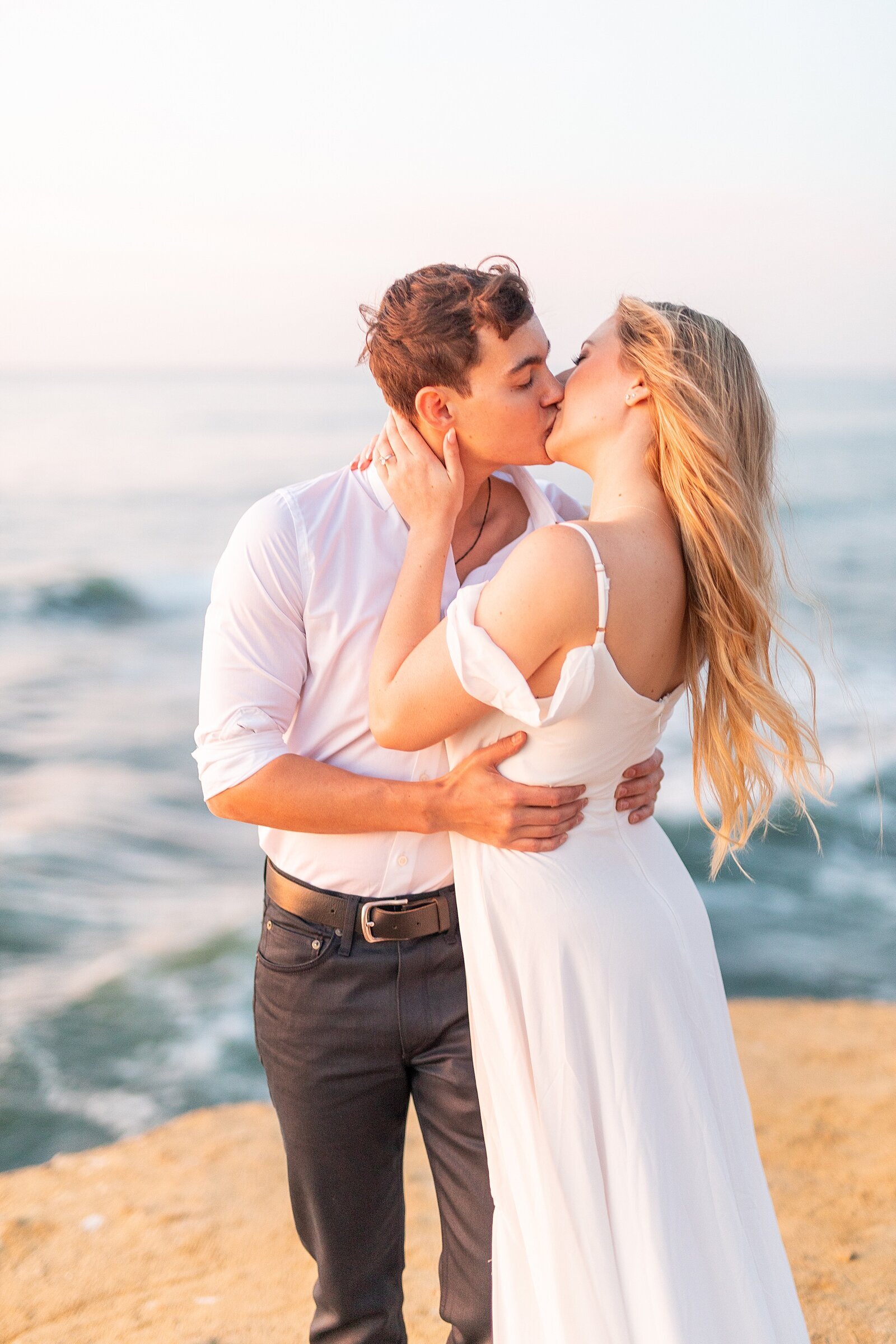 Couple kissing on the rocks of Sunset Cliffs in Point Loma, California.