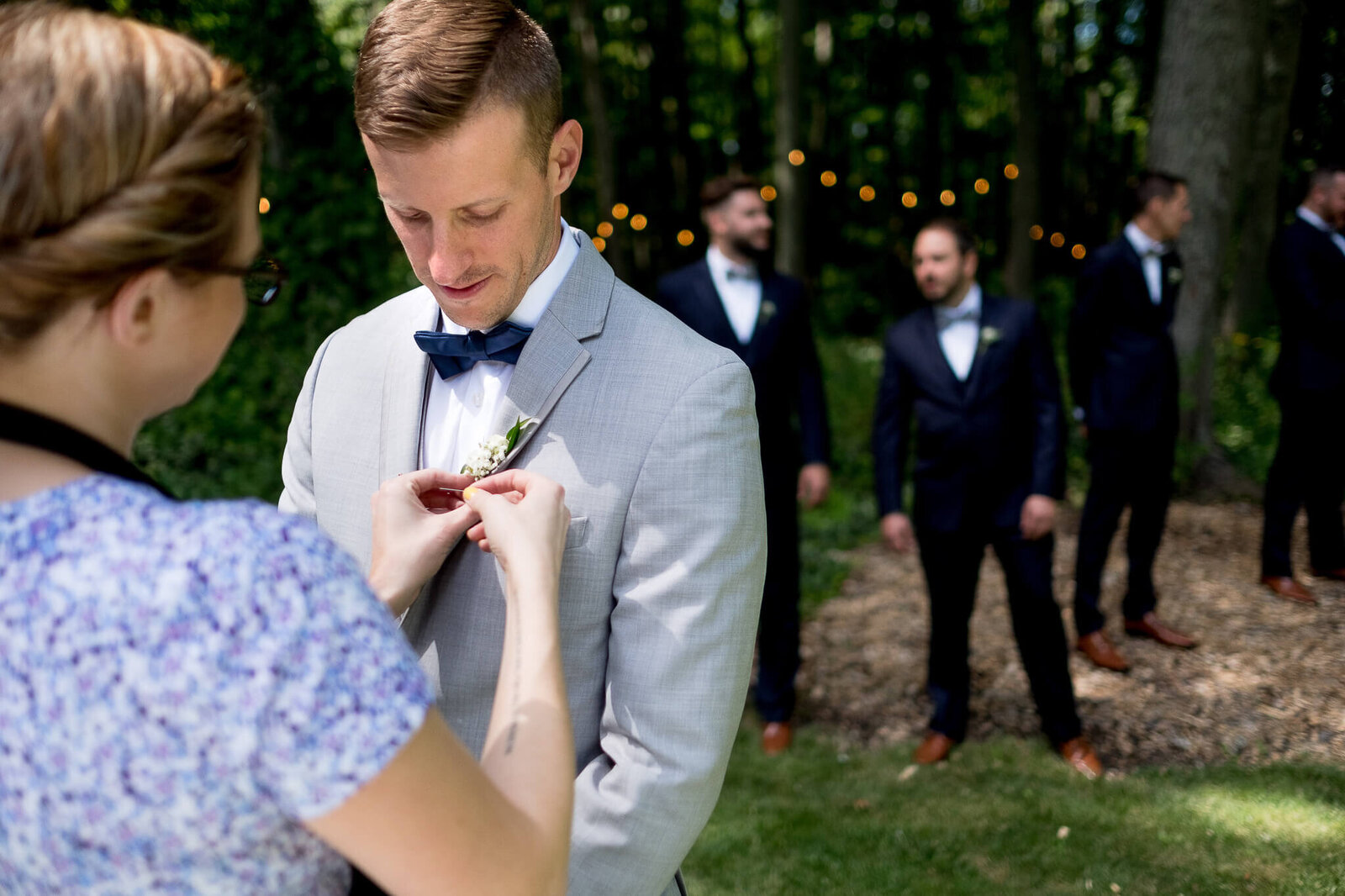 Wedding planner putting on groom's boutonierre.